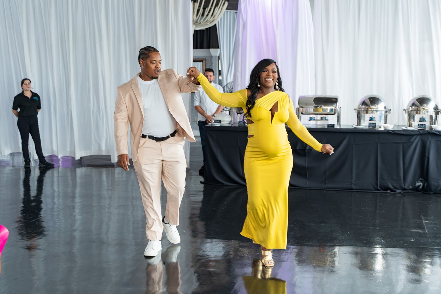 Two guests dancing together at an event, one wearing yellow and one in beige.