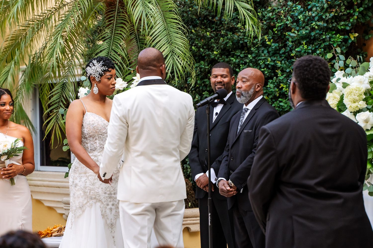 Elegant outdoor wedding ceremony with palm trees and formal attire.