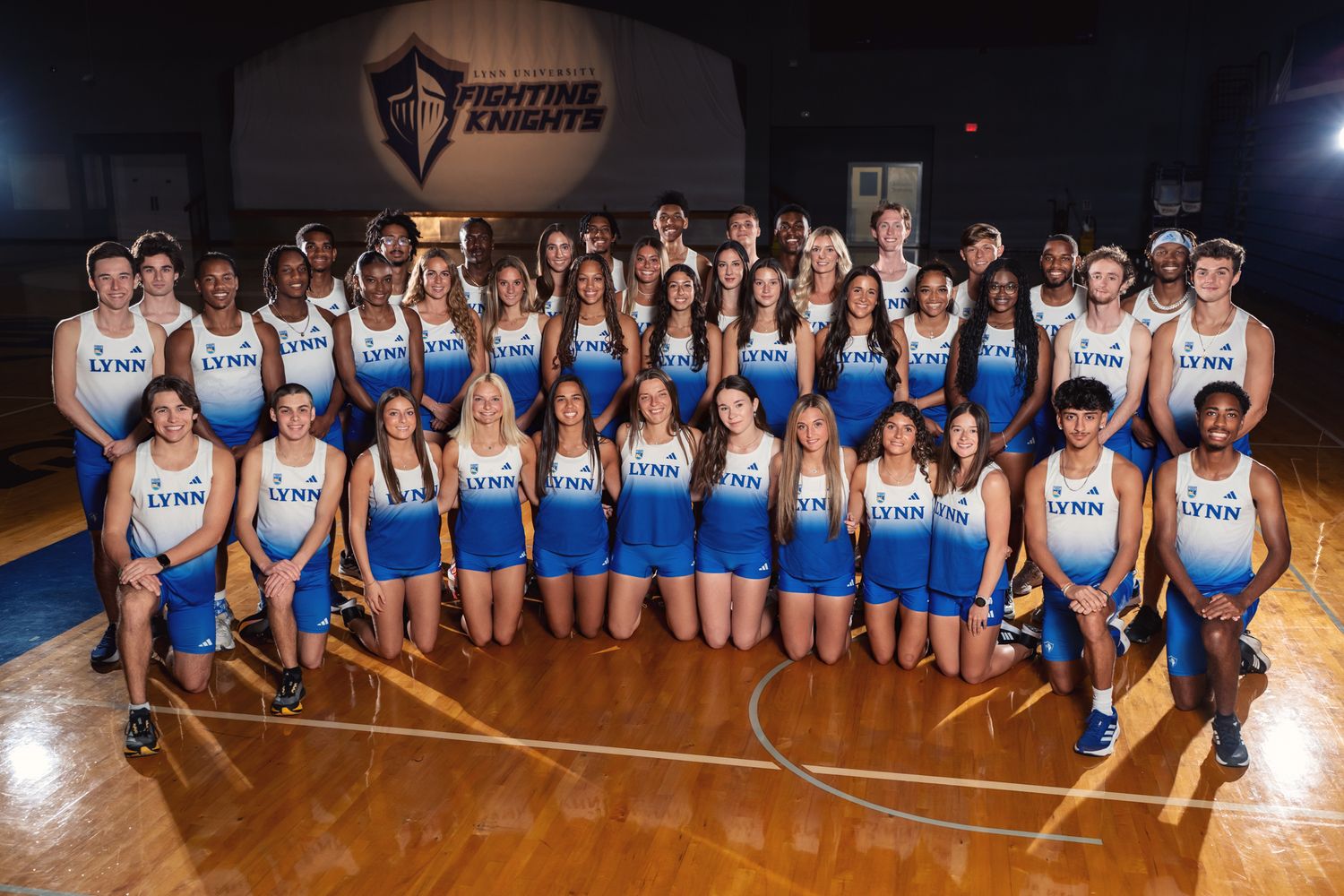 Large group photo of Lynn University athletic team members in white and blue uniforms on basketball court.