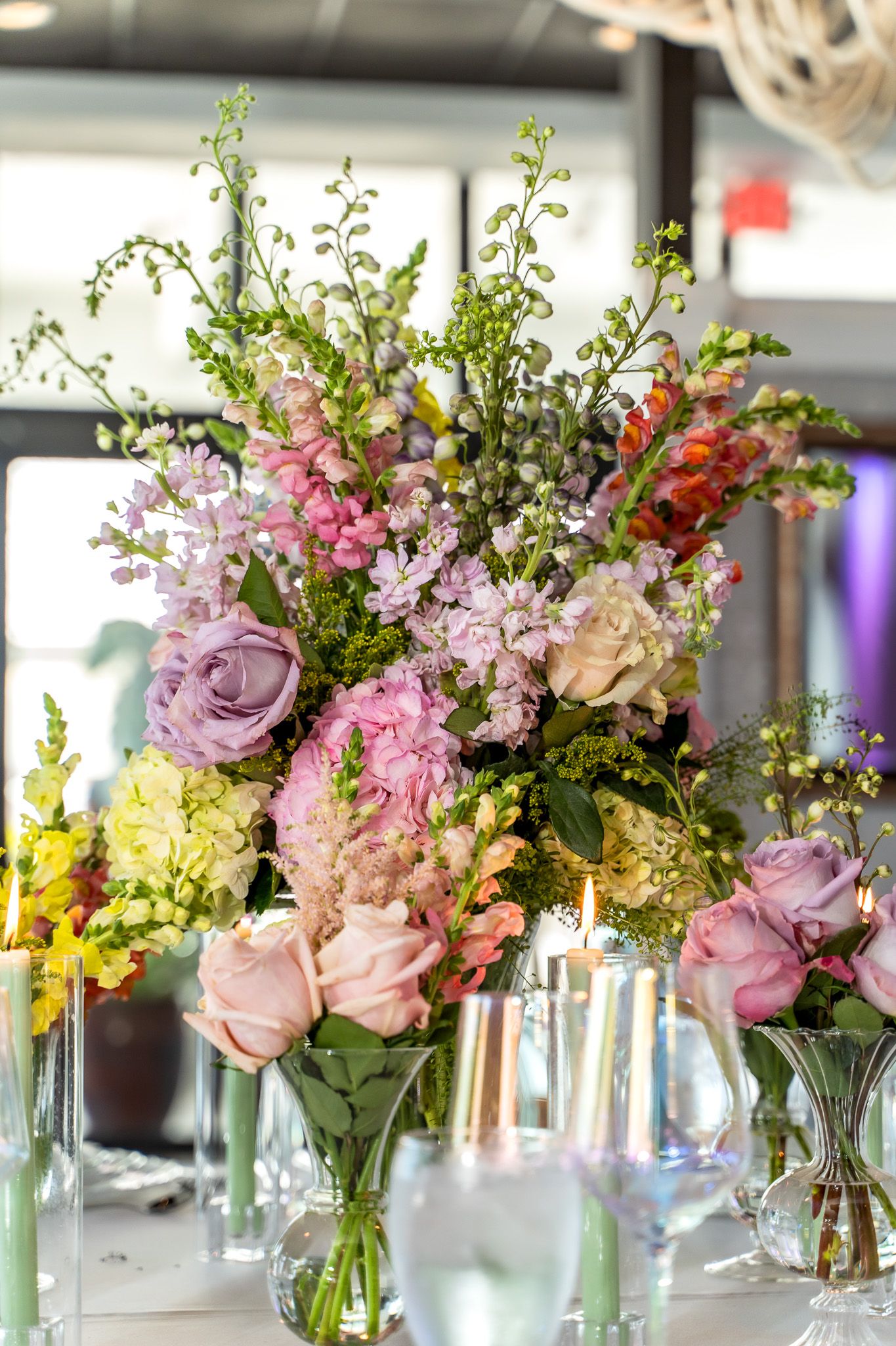Garden-inspired floral centerpiece with pink roses and wildflowers in glass vases.