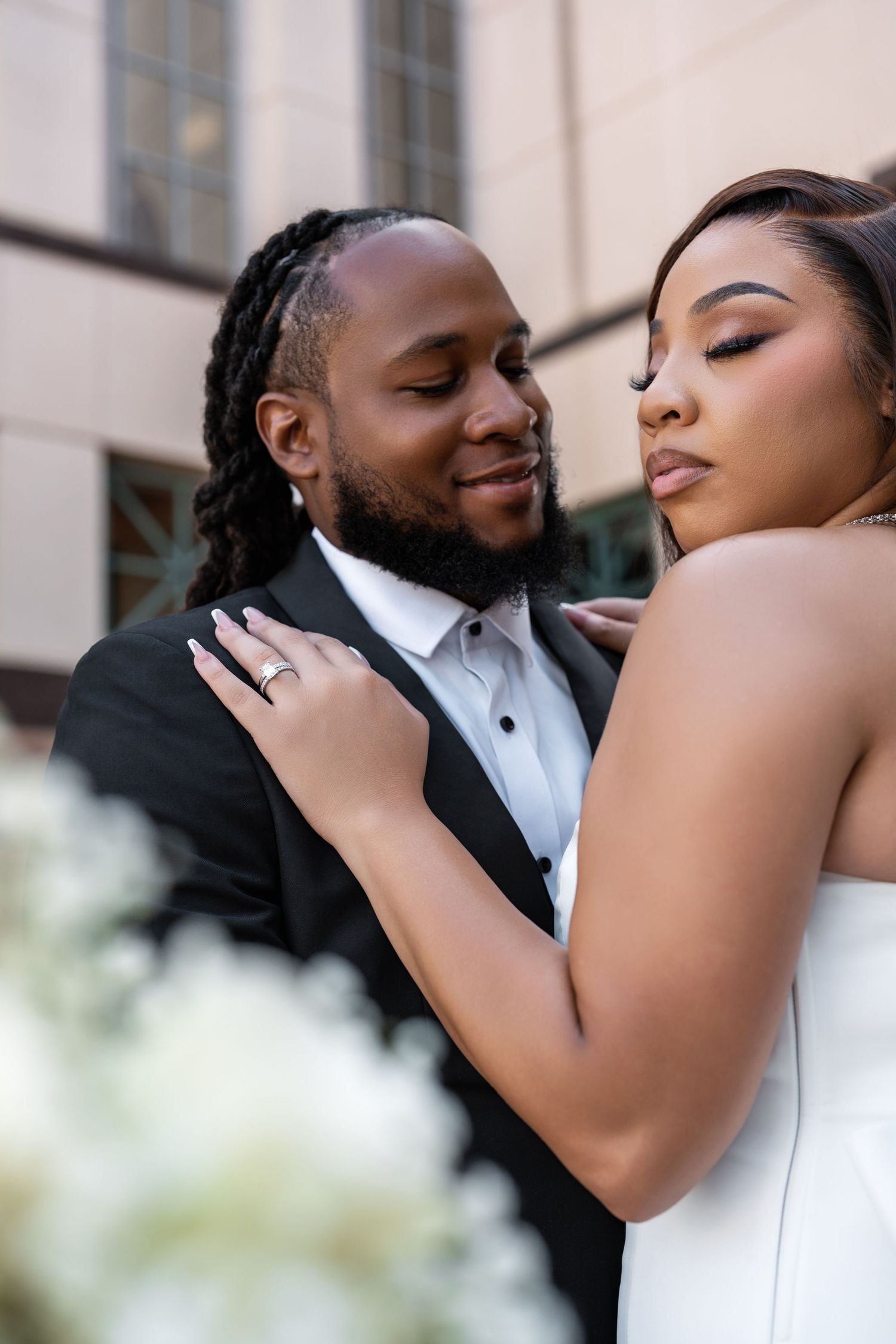 An intimate moment between a couple in wedding attire sharing a tender embrace outdoors.