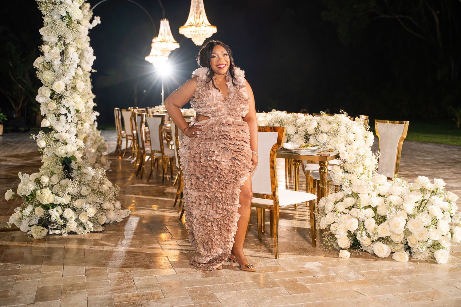 A glamorous evening wedding reception decorated with luxurious white floral arrangements and warm lighting.