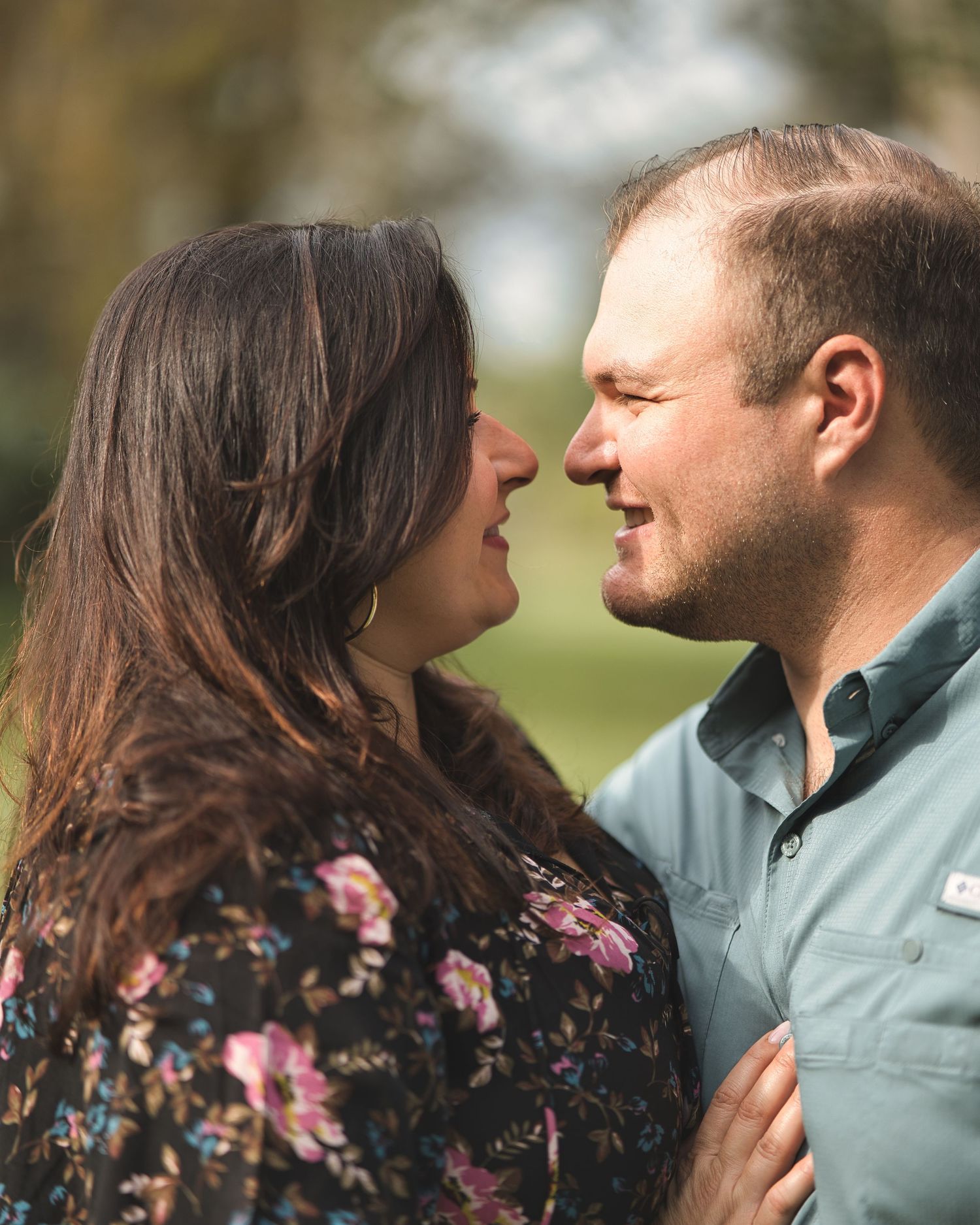Intimate moment shared between couple in casual attire against natural outdoor backdrop.