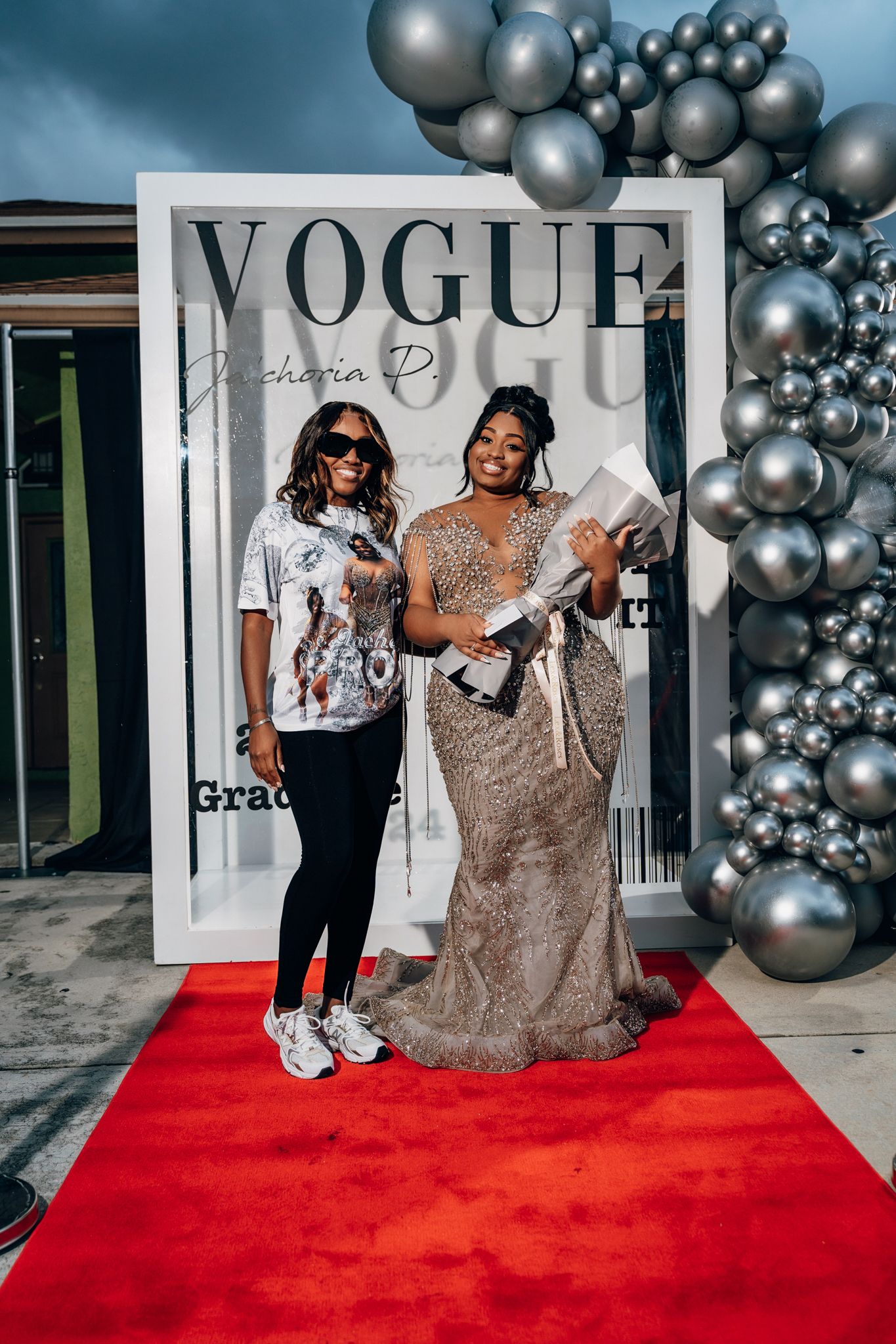 Graduation celebration photo with guest in casual wear posing on red carpet.