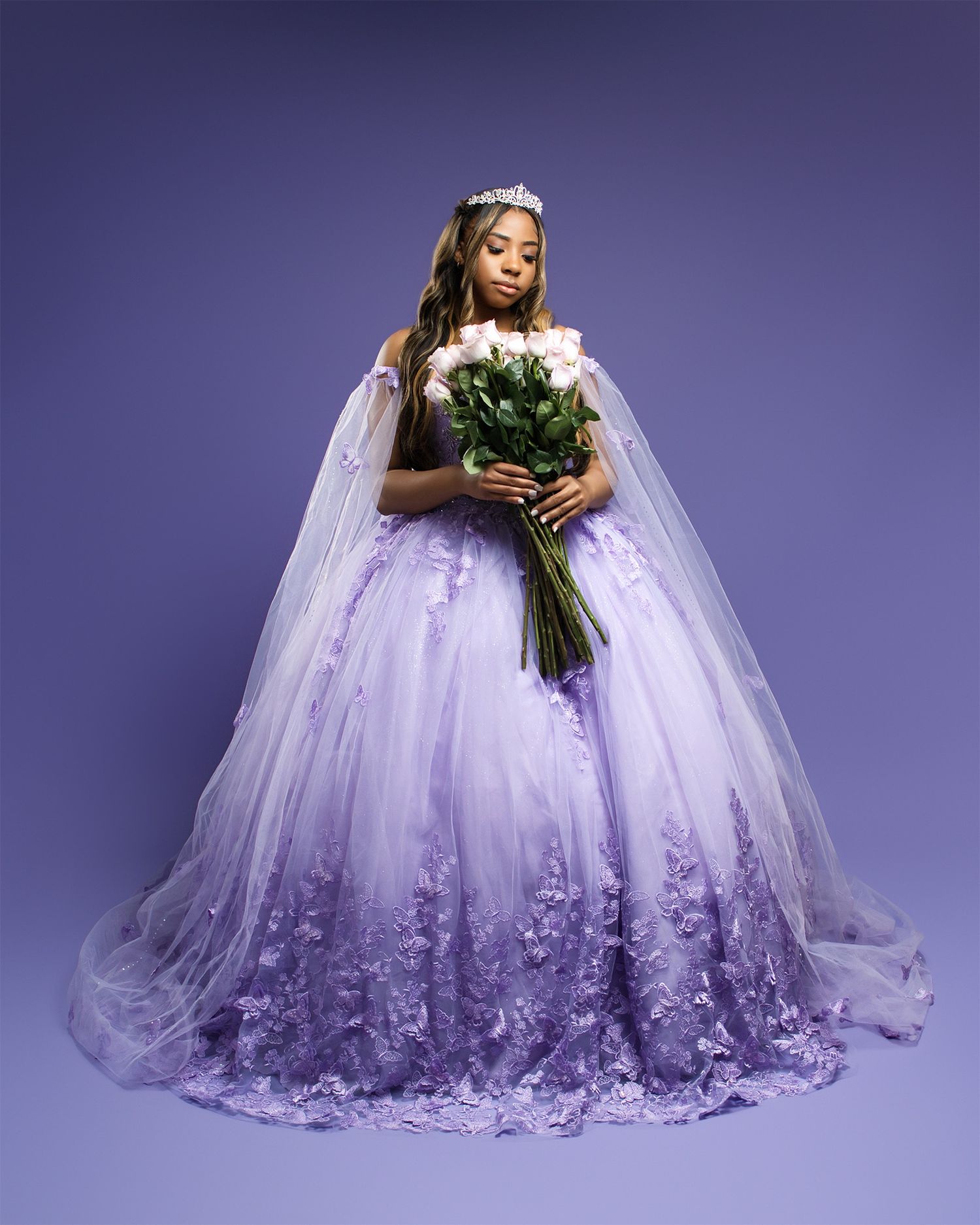 An elegant bridal portrait in a lavender lace ball gown holding white flowers.