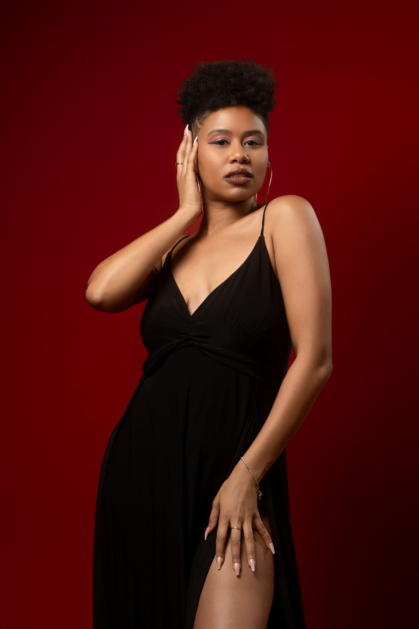 Dramatic fashion portrait in black dress against deep red background.