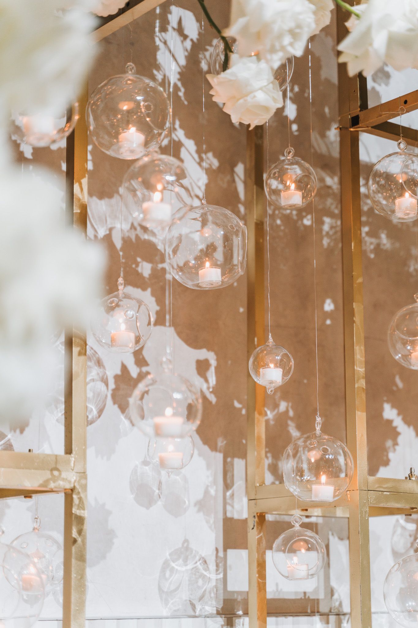 Glass orb candle holders and white floral decorations create an ethereal ceiling display at an elegant wedding.
