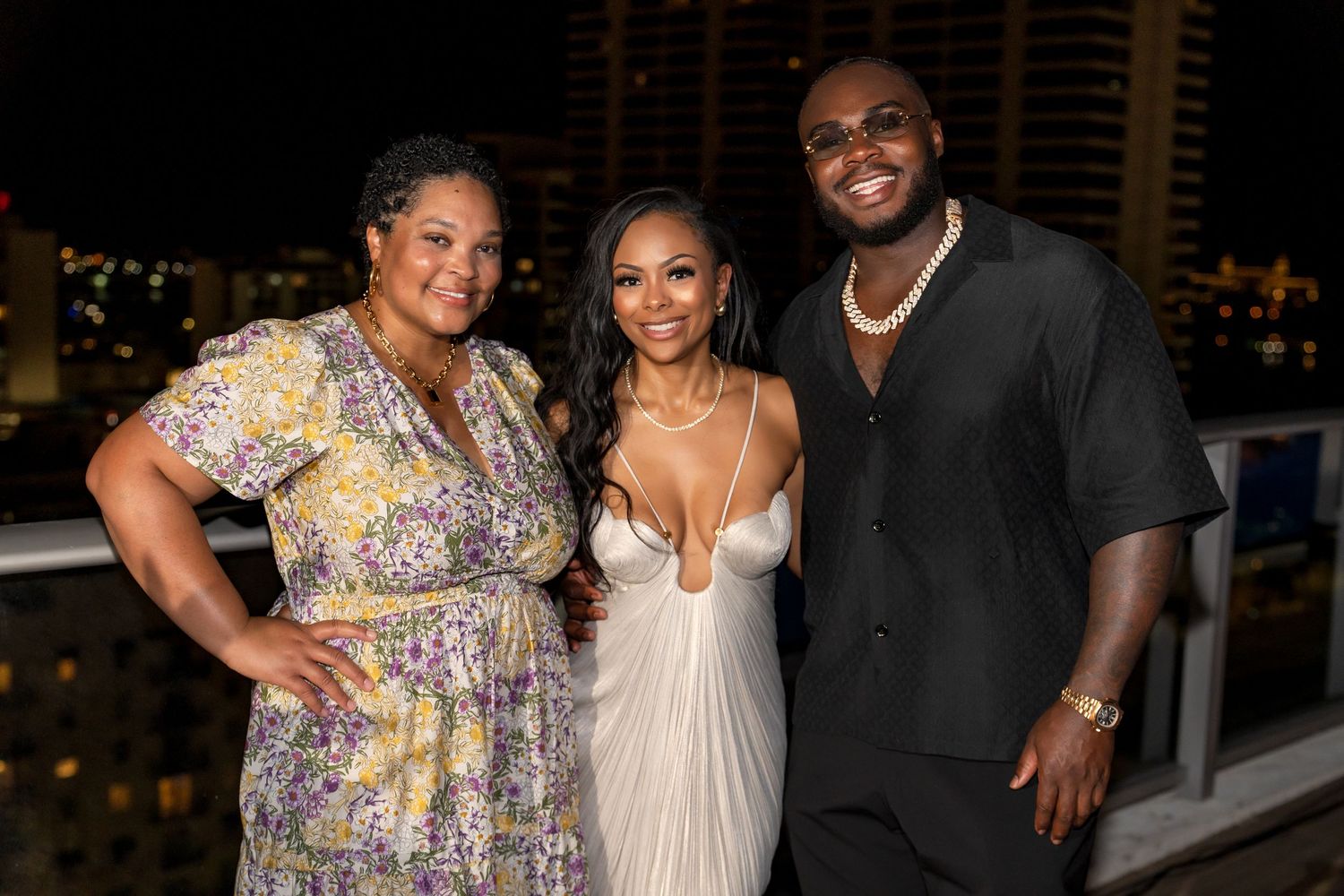 Three people in formal attire posing together at an evening celebration.