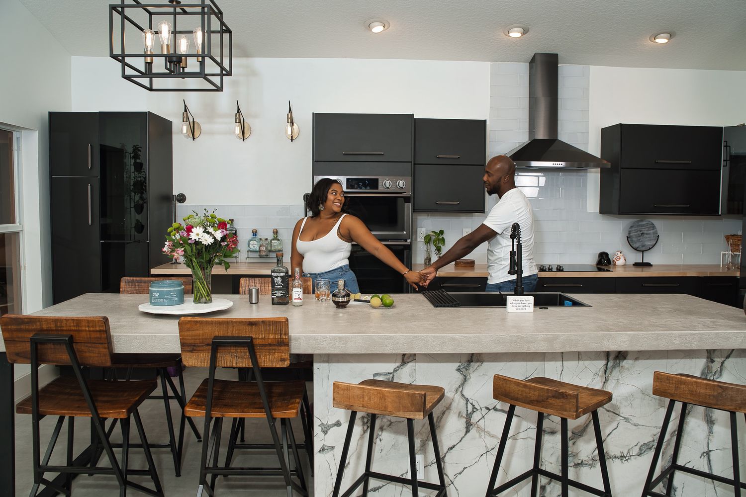 A couple having fun and being playful in their spacious kitchen with bar stools.
