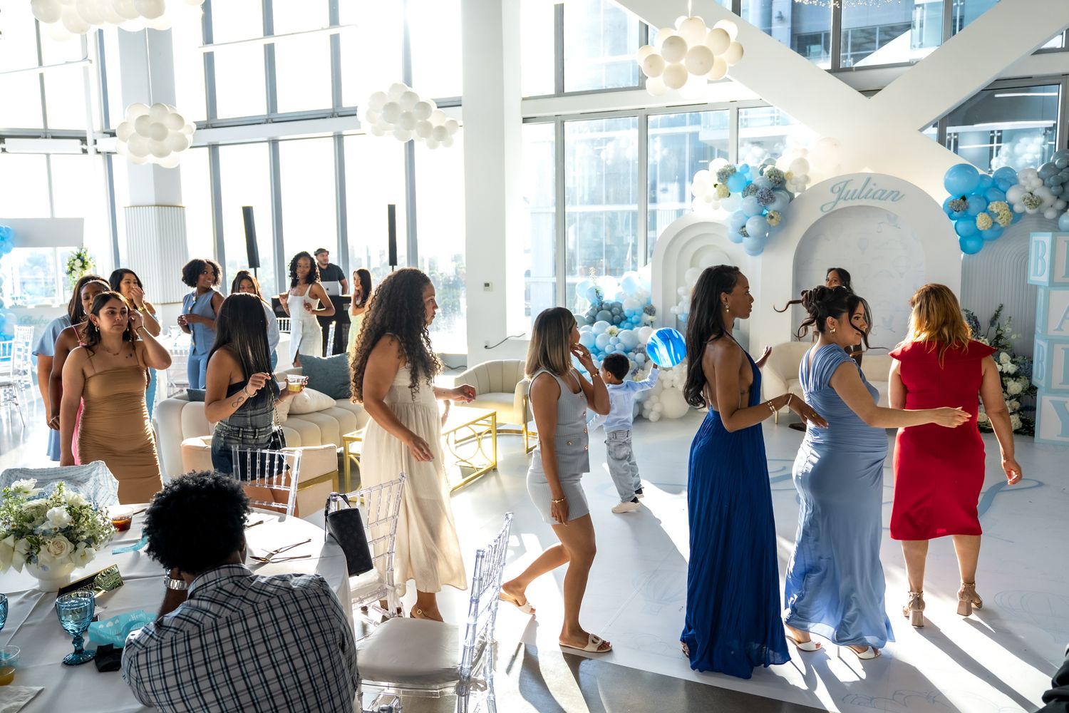 Guests mingling and socializing at elegant baby shower with blue and white decor.