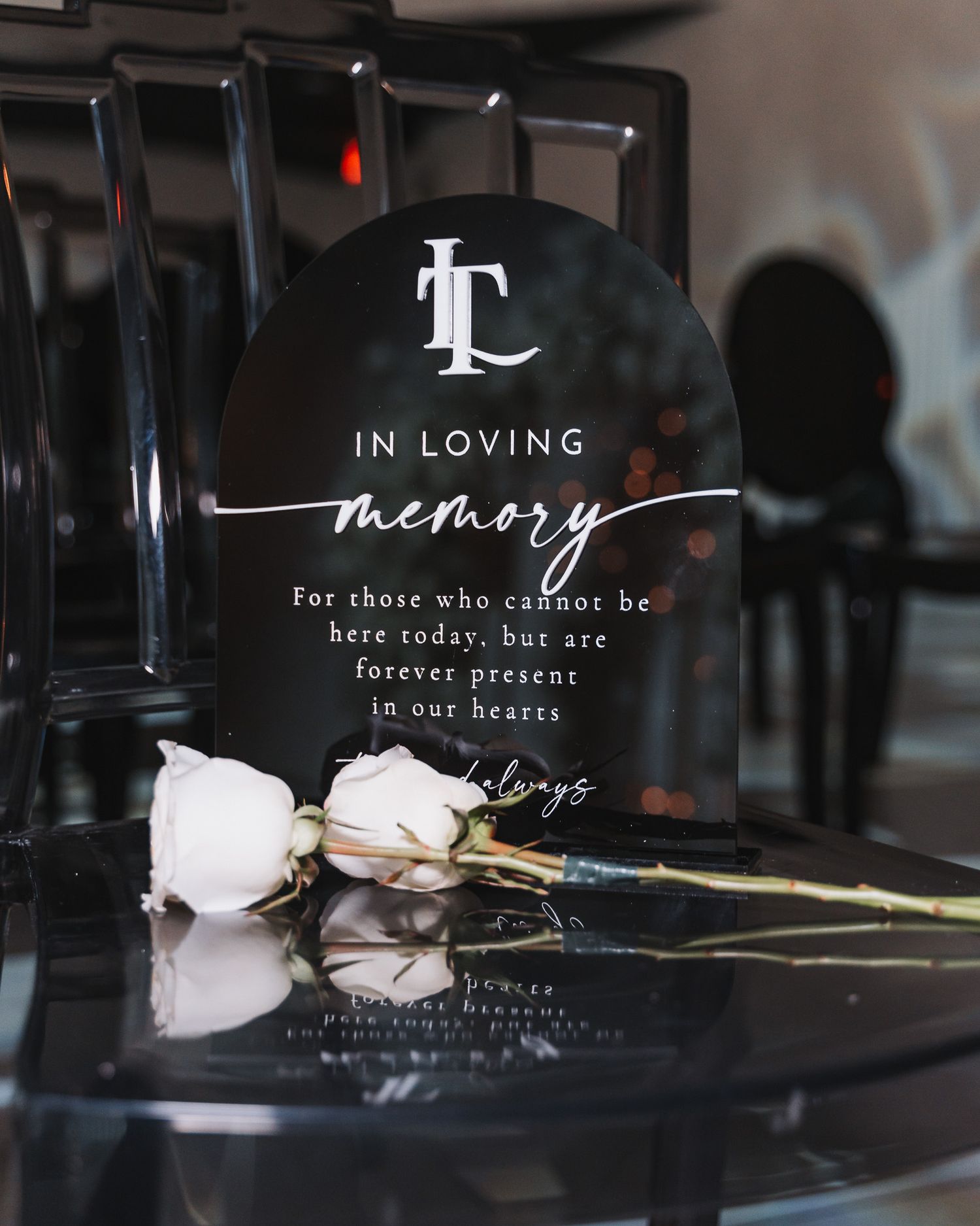 Memorial sign with roses displaying In Loving Memory text against dark background.