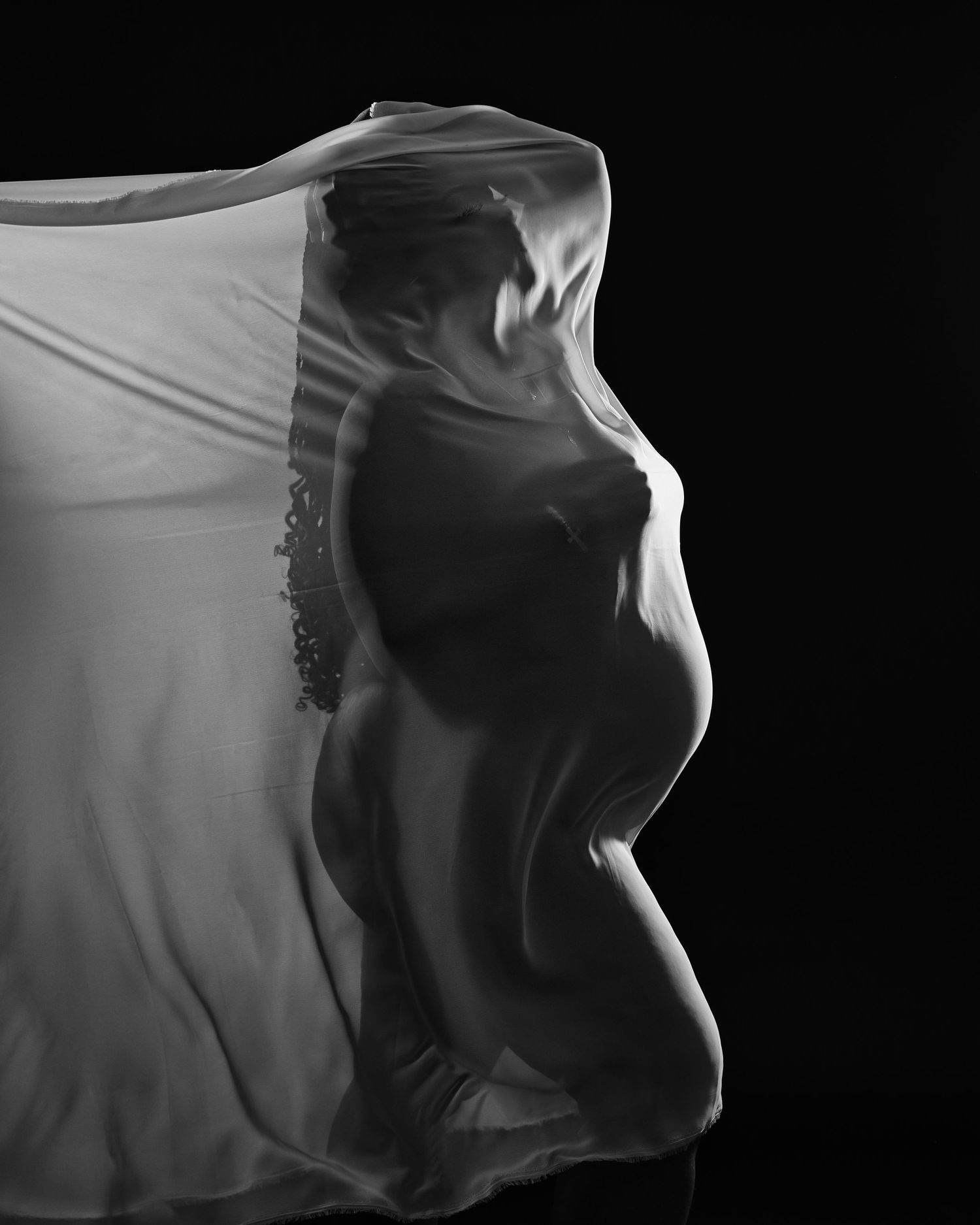 Artistic black and white silhouette profile photo with flowing fabric against dark background.