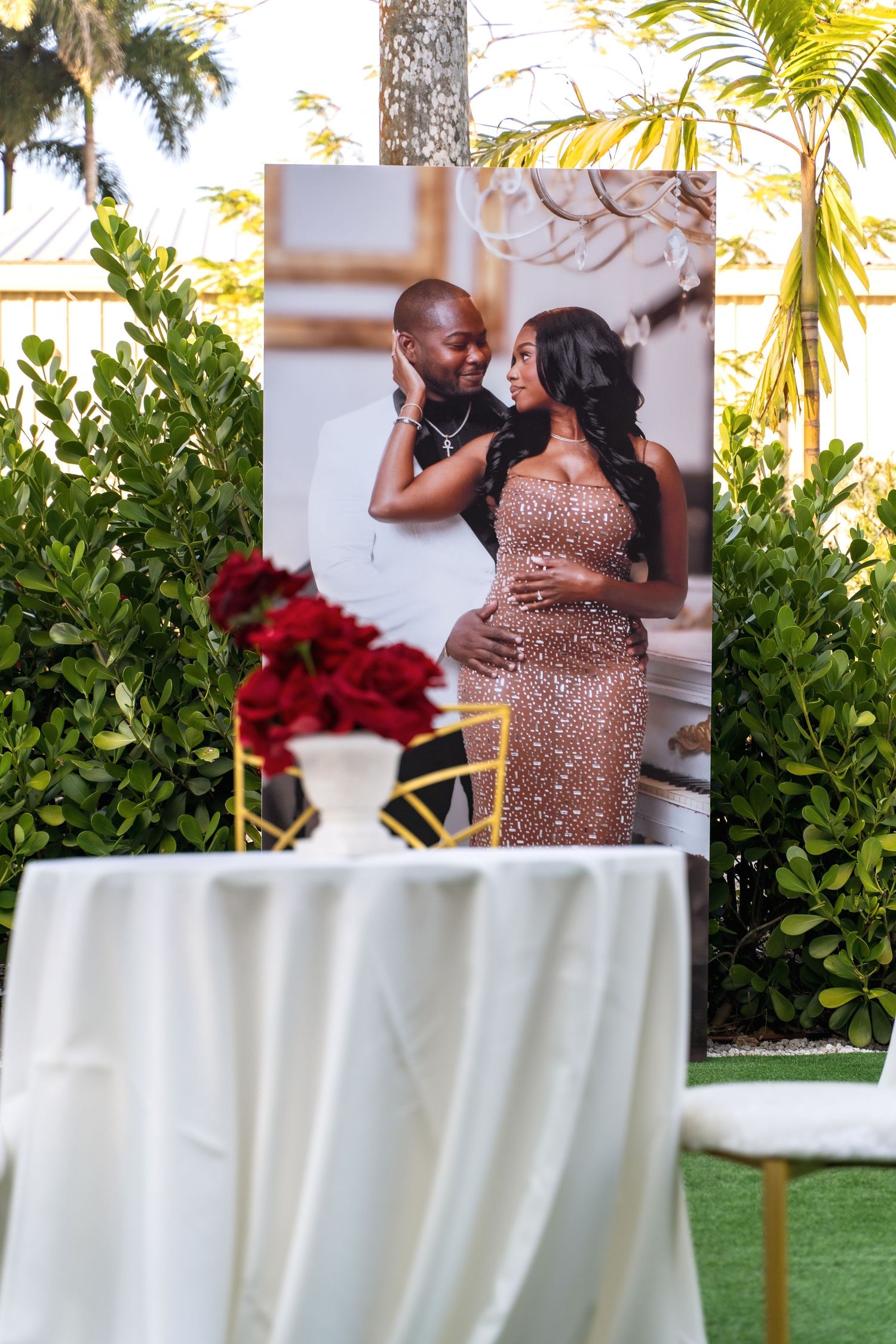 Elegant outdoor event setup with white tablecloths and tropical palm trees in the background.