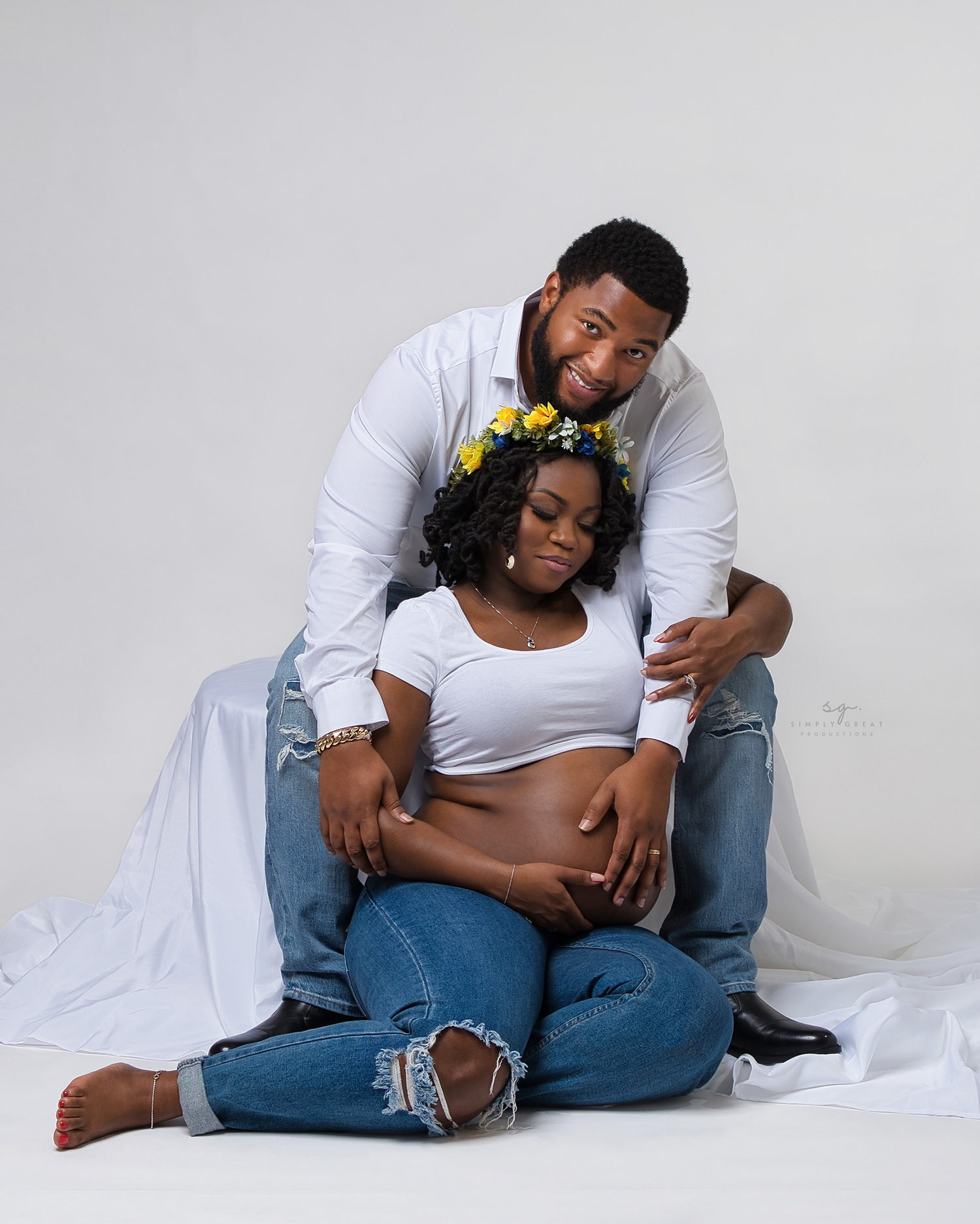 Intimate maternity photo of couple relaxing on white fabric.