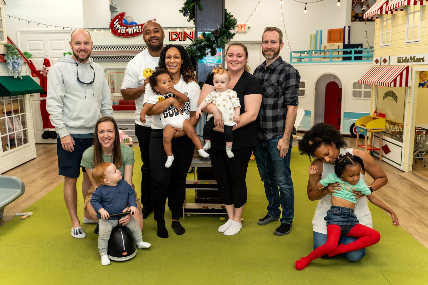Group photo in a colorful playroom with children and adults gathered on stairs.