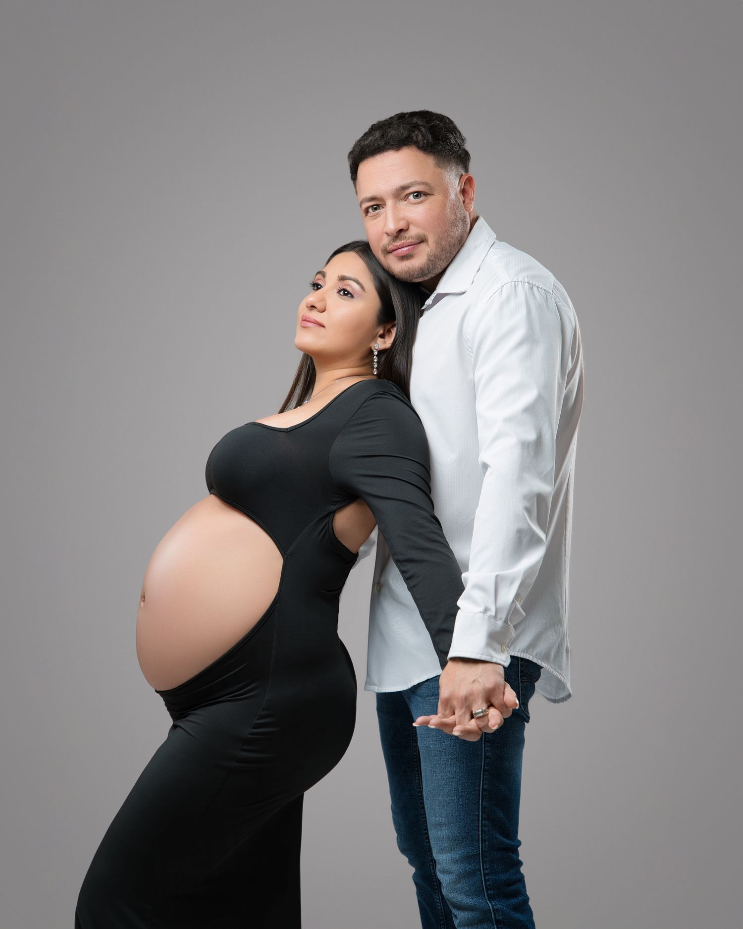 Stylish maternity studio portrait of couple in black and white casual attire.