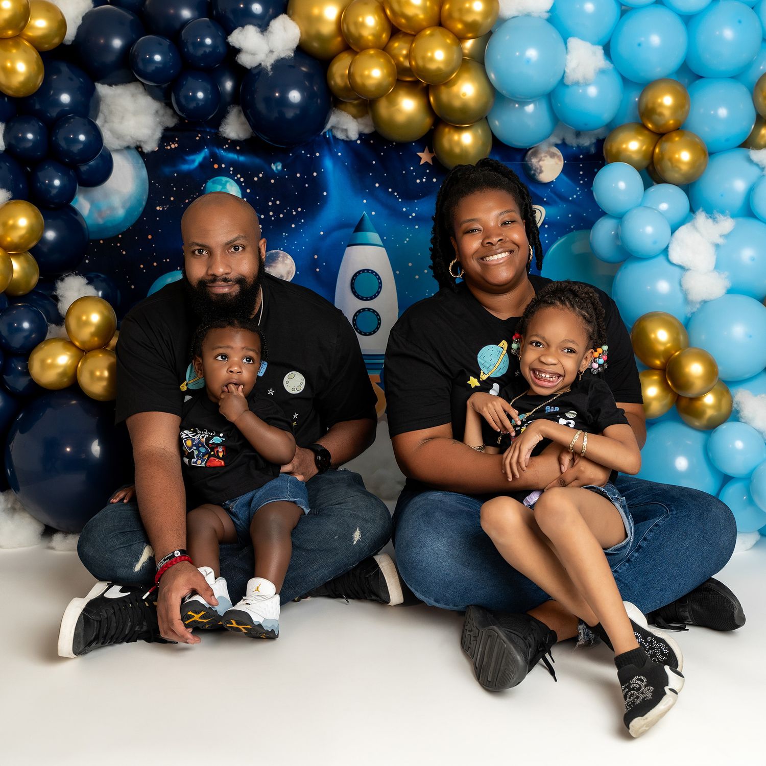Family portrait with space-themed balloon decor featuring navy, gold, and light blue colors.