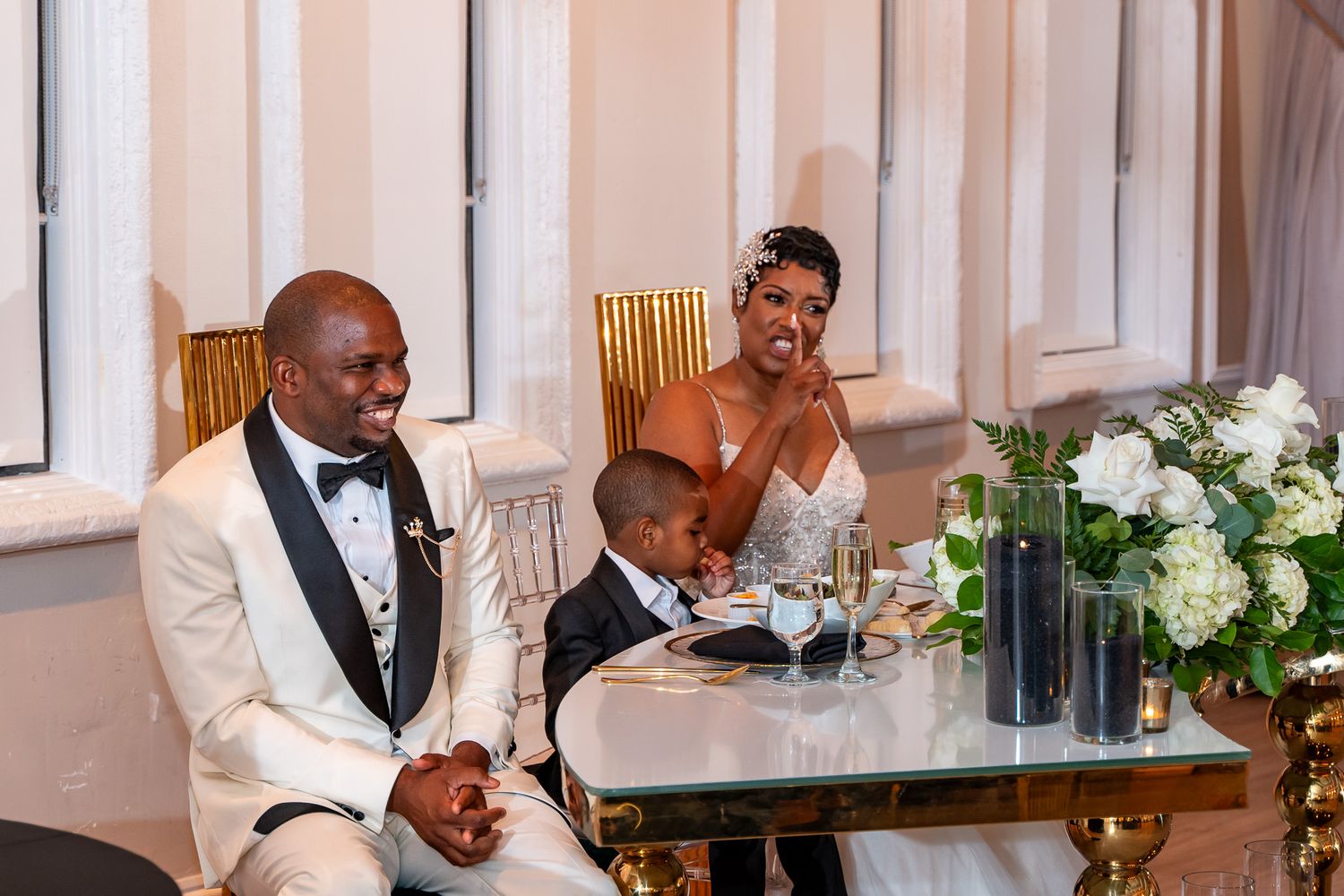 Family moment at the reception table with elegant floral centerpieces and white decor.