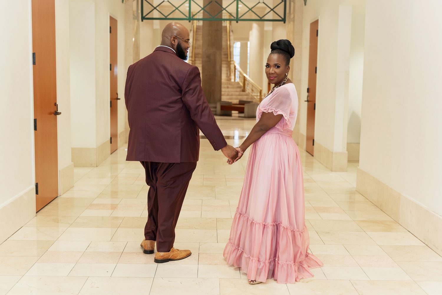 A couple dancing together in an elegant hallway, with the bride wearing a flowing pink dress.