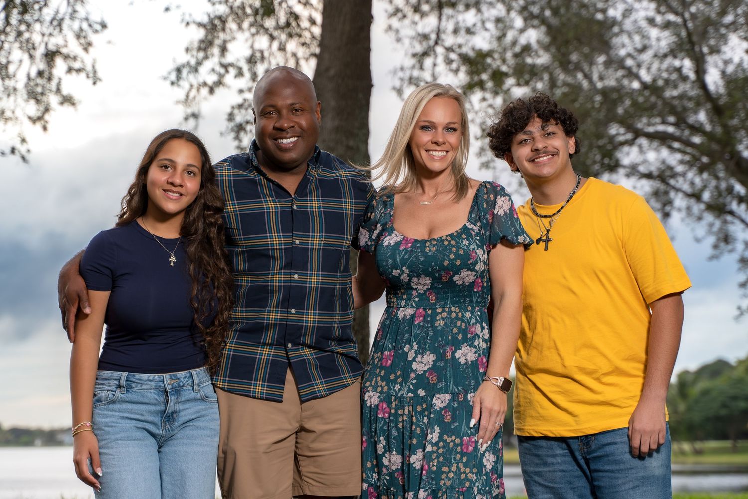 A group of people wearing casual attire pose together outdoors on a sunny day.