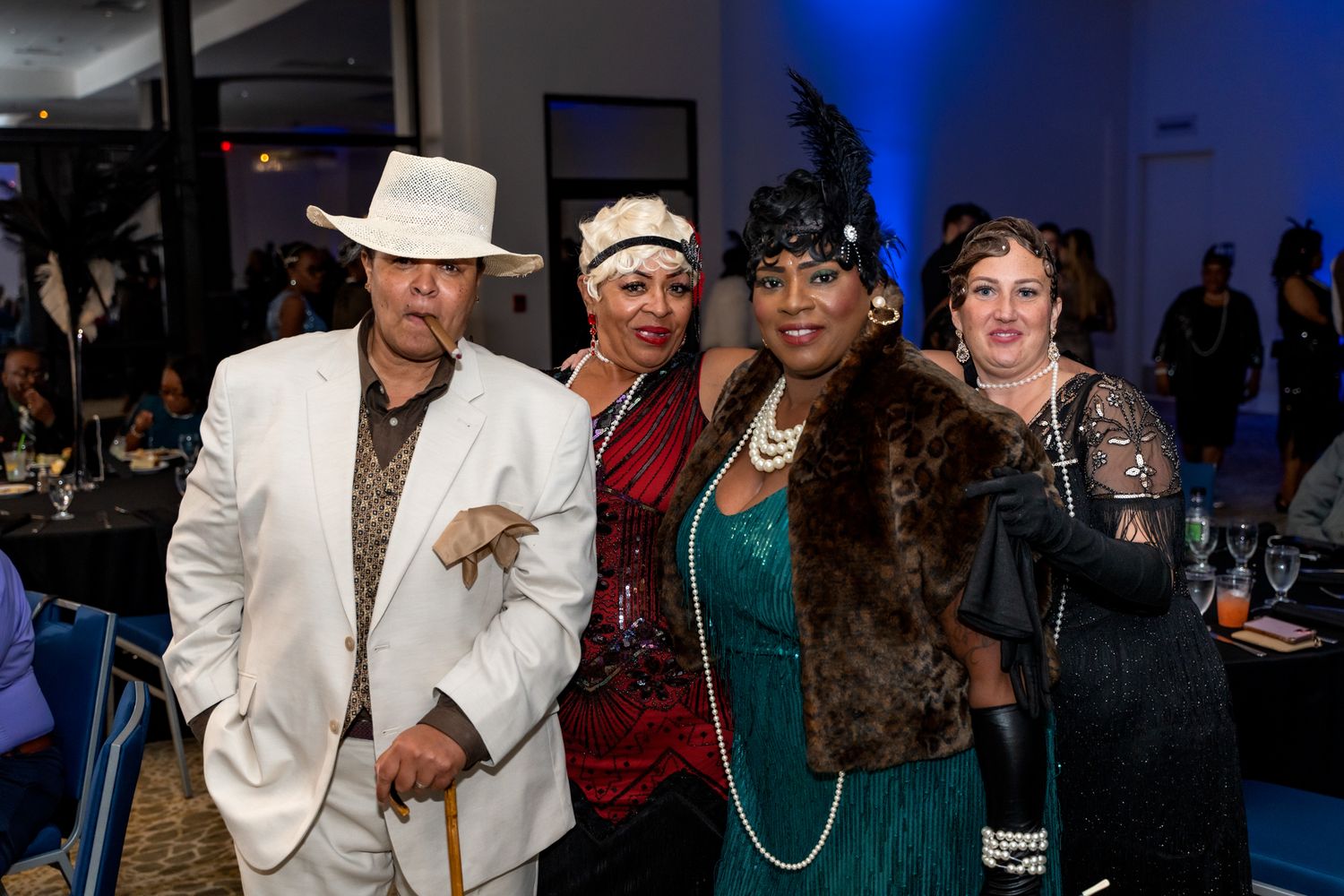 Attendees in vintage-inspired formal wear pose together at an elegant evening event.