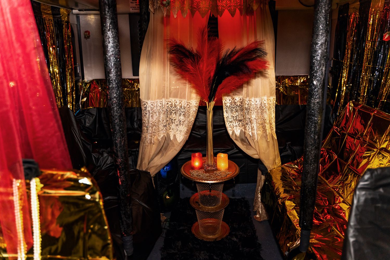 Dramatic red and black decor with feathers and candlelight creating a moody atmosphere.