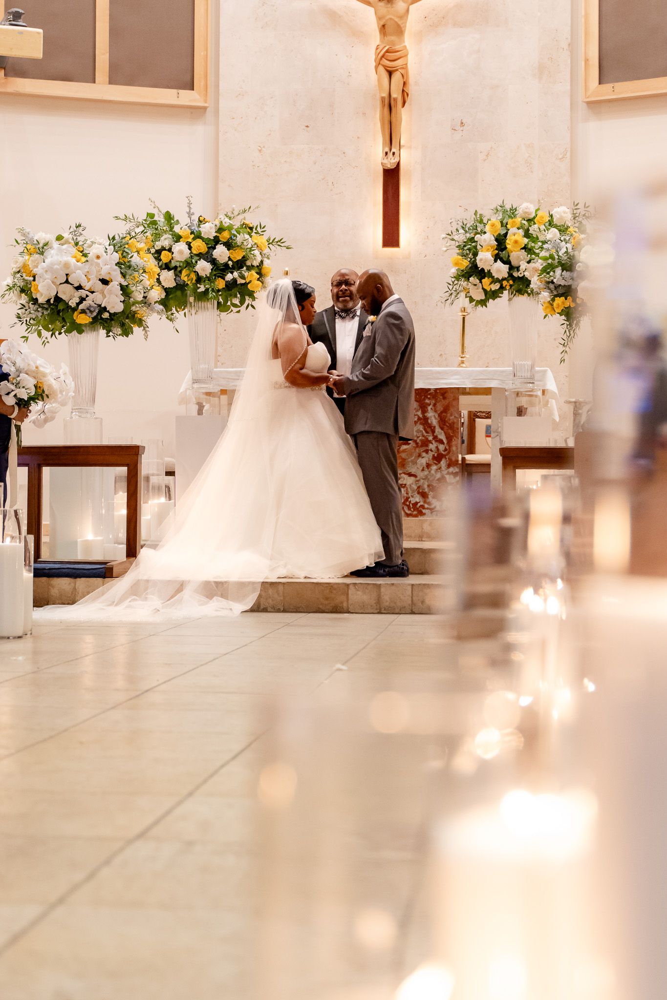 Romantic wedding moment at church altar with beautiful floral arrangements and candle lighting.