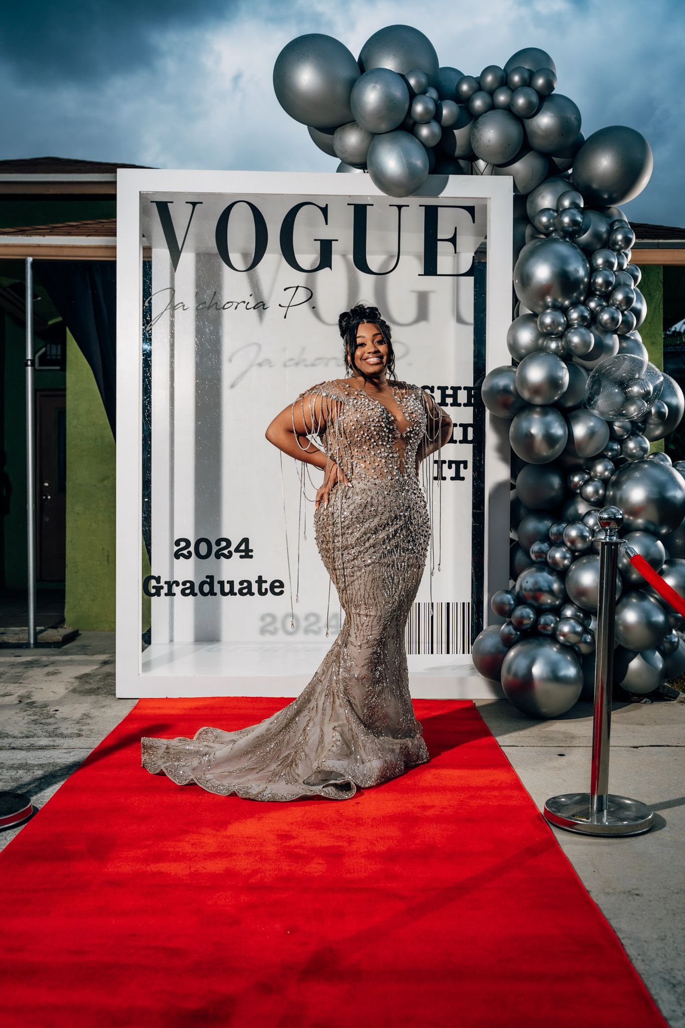 Full length shot of sparkling mermaid gown on red carpet with silver balloon arch.