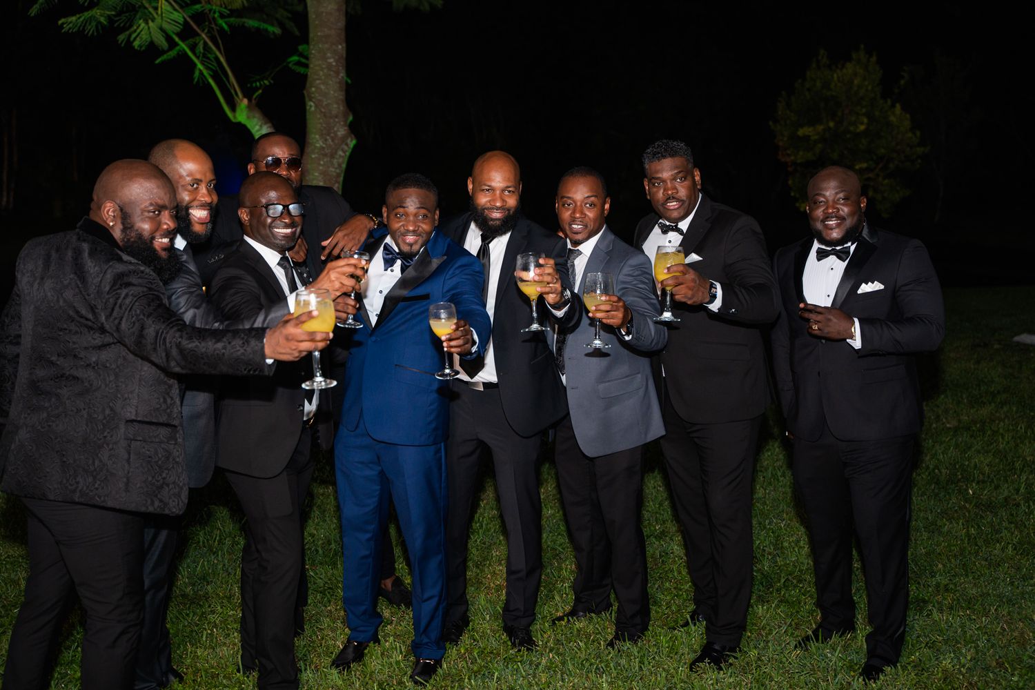 A group celebrating with champagne toasts at an outdoor evening event.