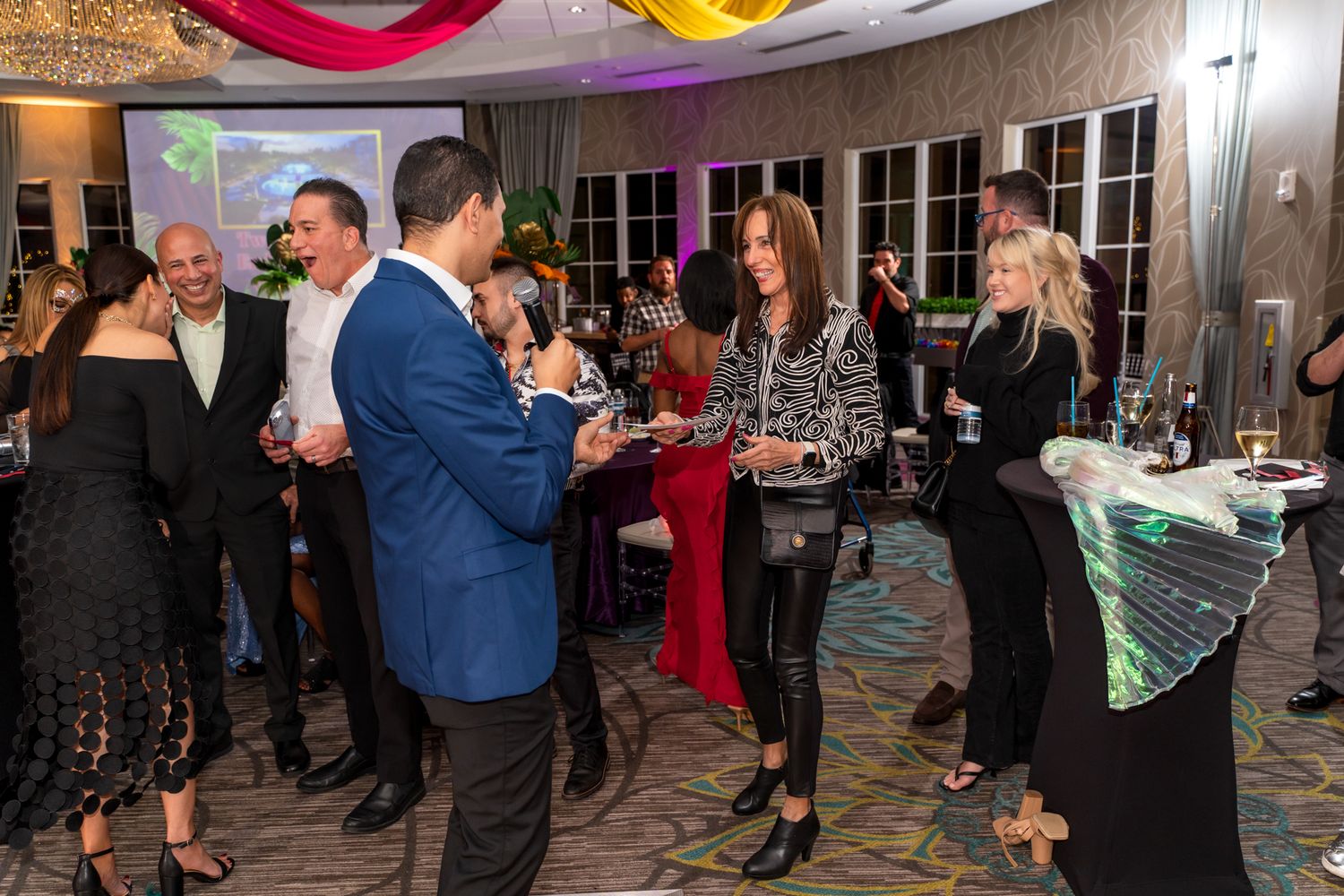 Elegant party guests mingling and socializing at an evening event with decorative lighting.