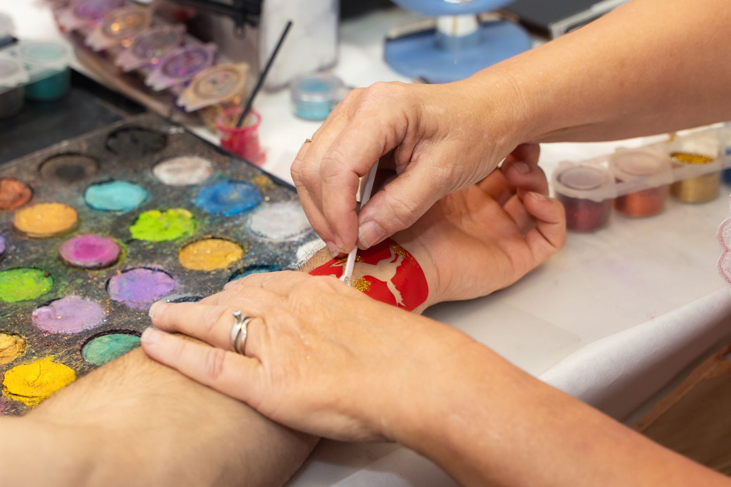 Close-up of hands applying colorful nail polish from a vibrant palette during manicure service.