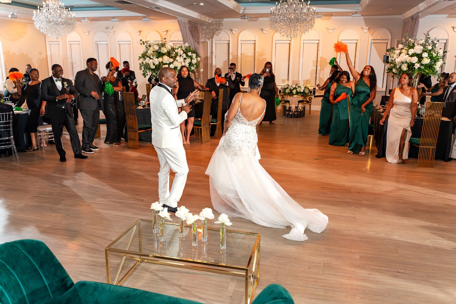Couple dances energetically during their wedding reception in an elegant ballroom with crystal chandeliers.