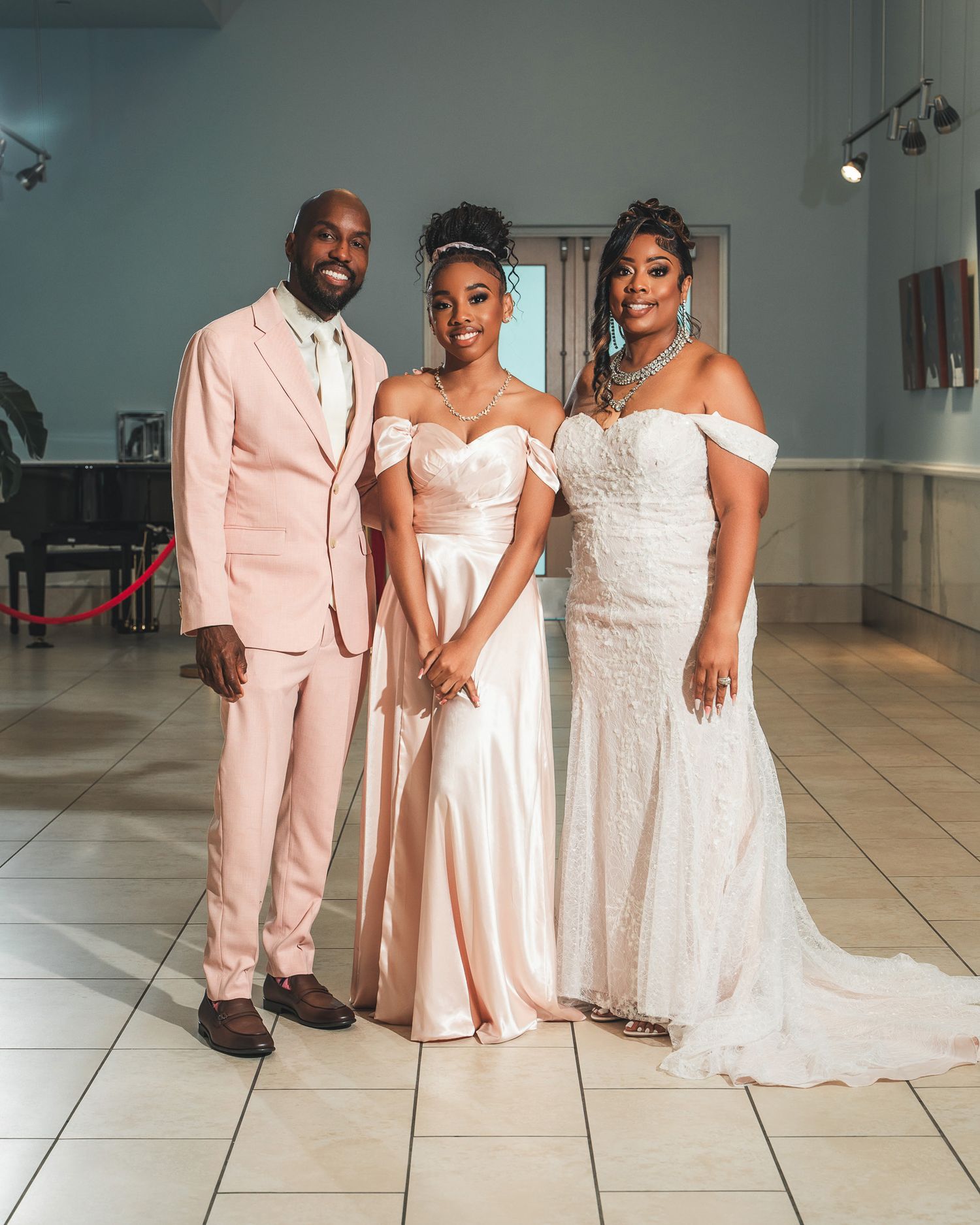 Wedding party poses in formal attire with the groom in pink suit and attendants in elegant dresses.
