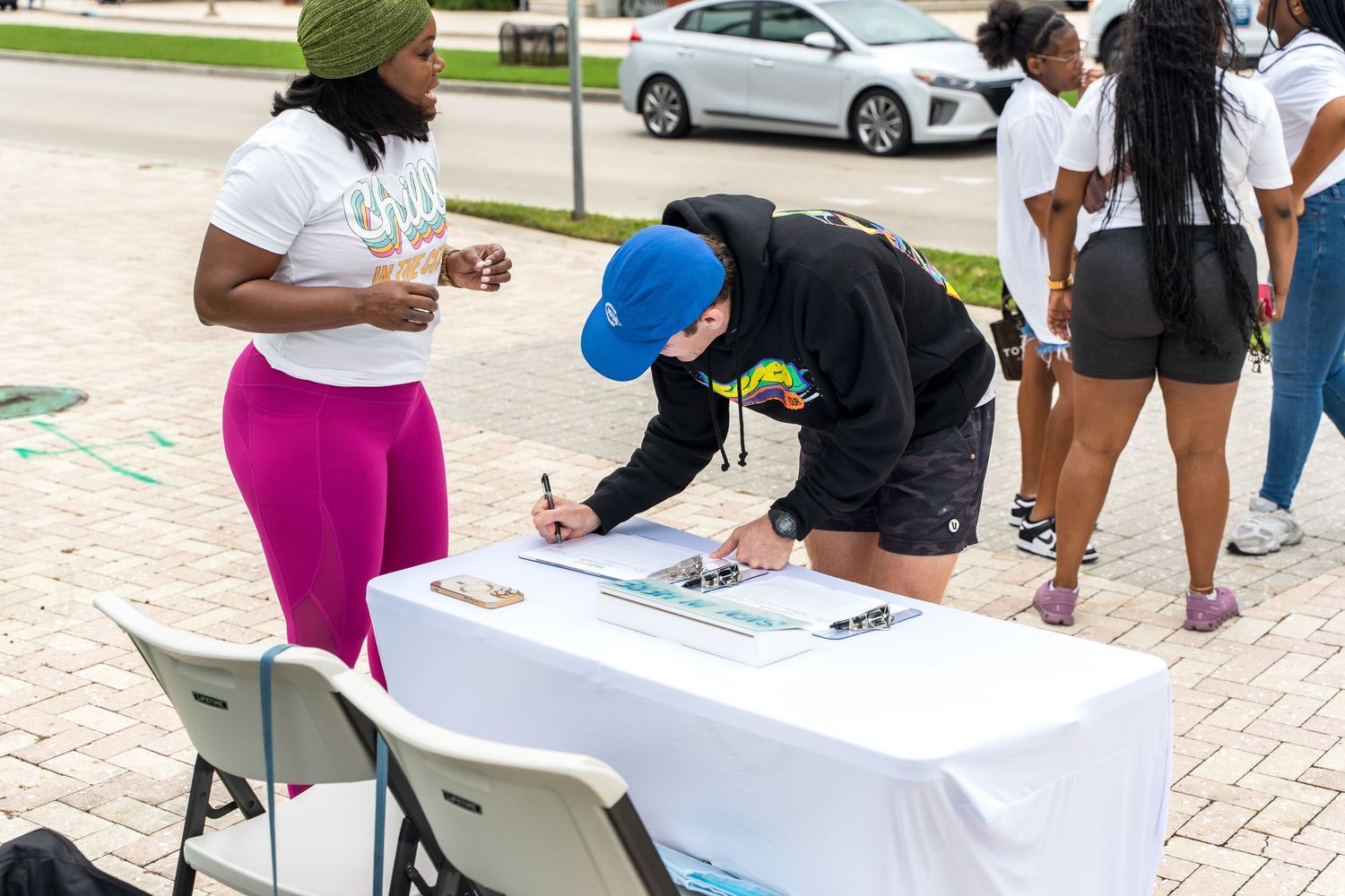 People signing up at registration table at outdoor community event.