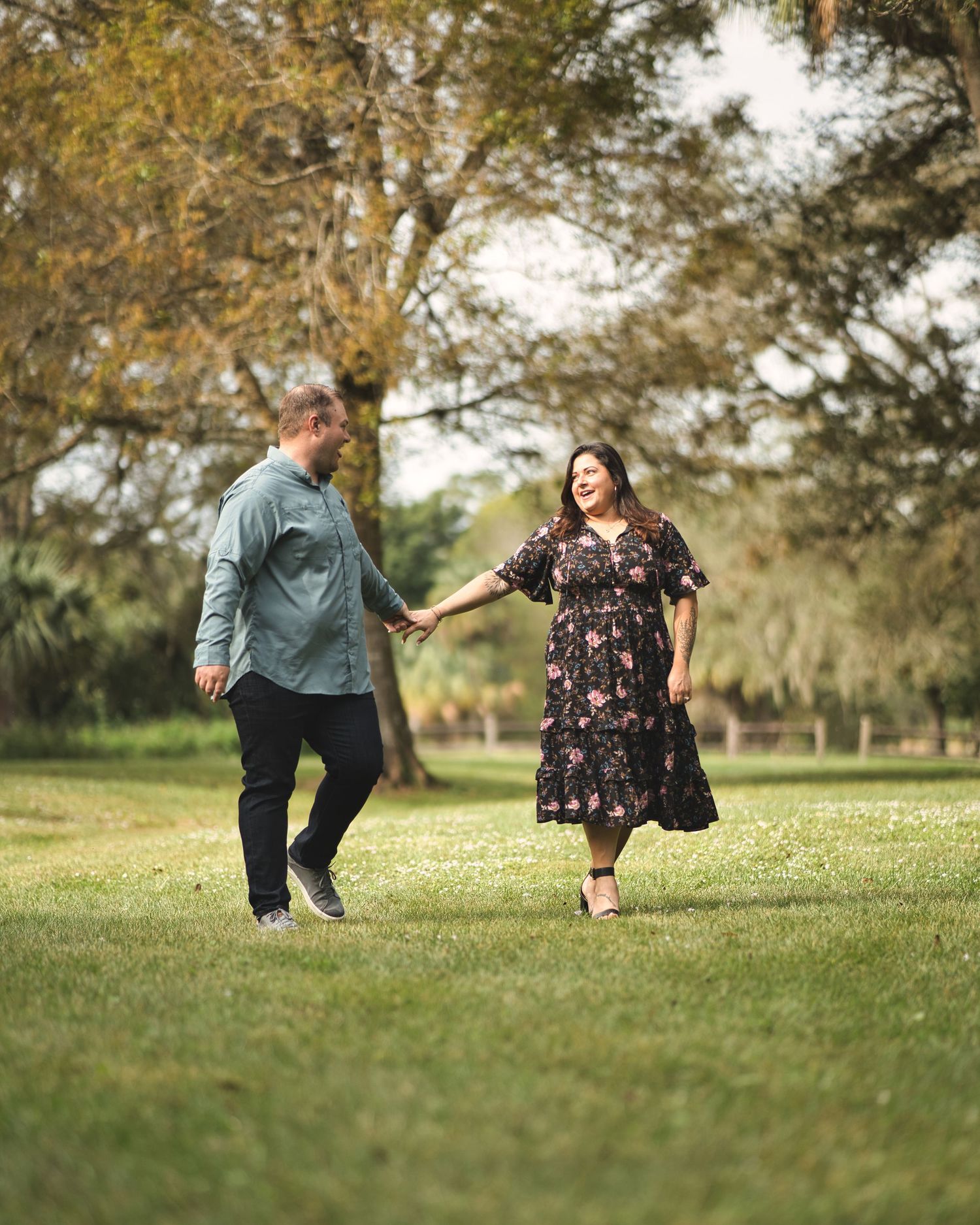 A loving couple dancing together on grass in a park setting.