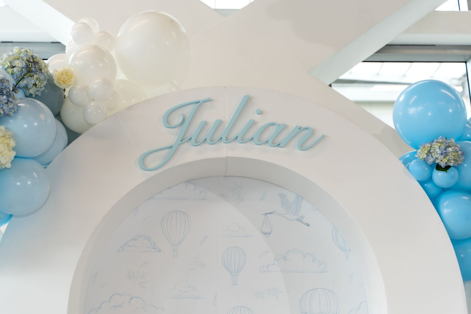 White decorative arch with blue accents and Julian text for a baby celebration.