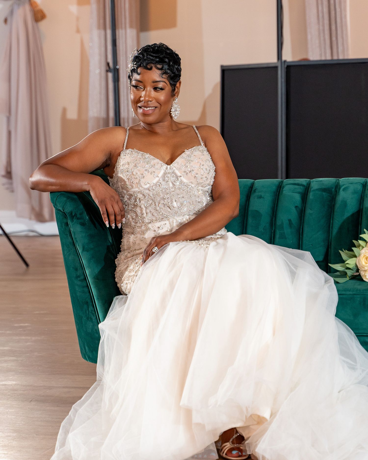 An elegant bridal portrait featuring a beaded sweetheart neckline gown and emerald velvet seating.
