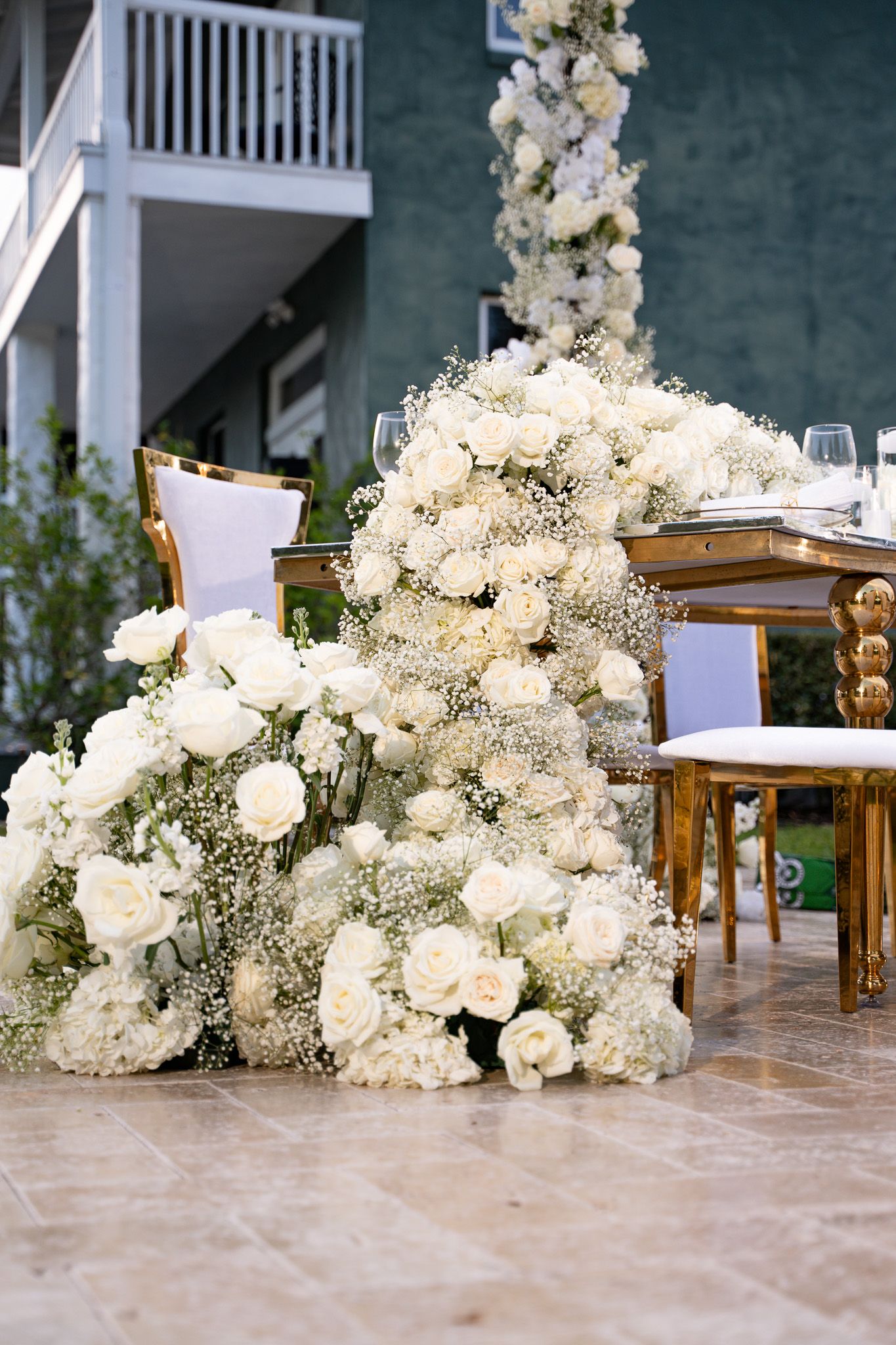 A series of elegant white floral arrangements with roses and baby's breath decorating a wedding venue entrance.