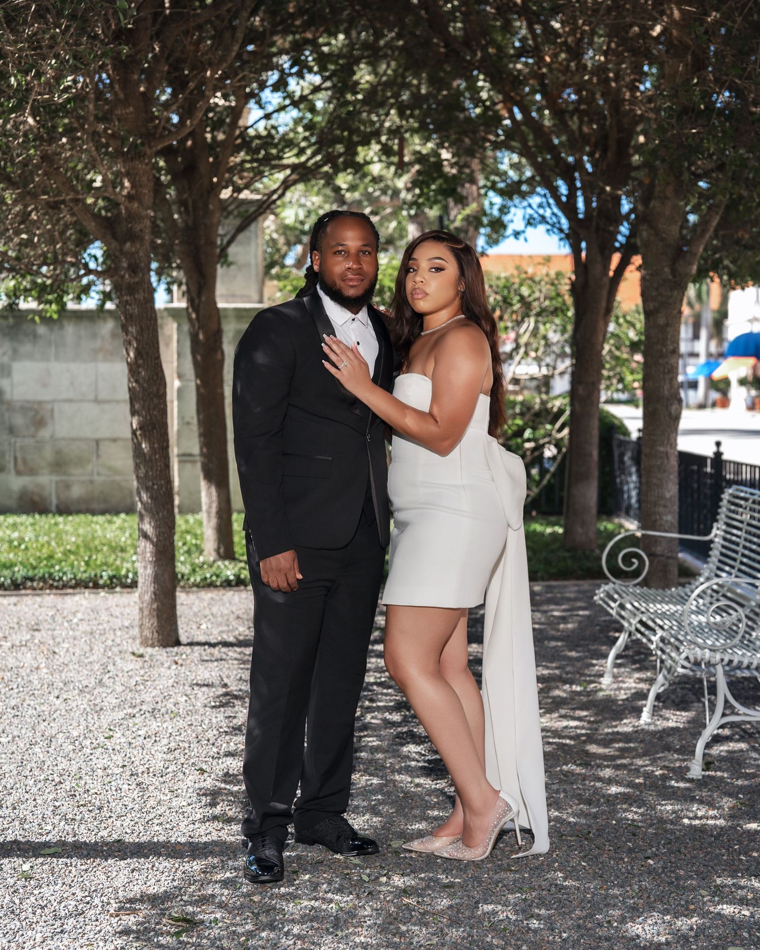 Garden wedding portraits taken among trees and benches in dappled sunlight.