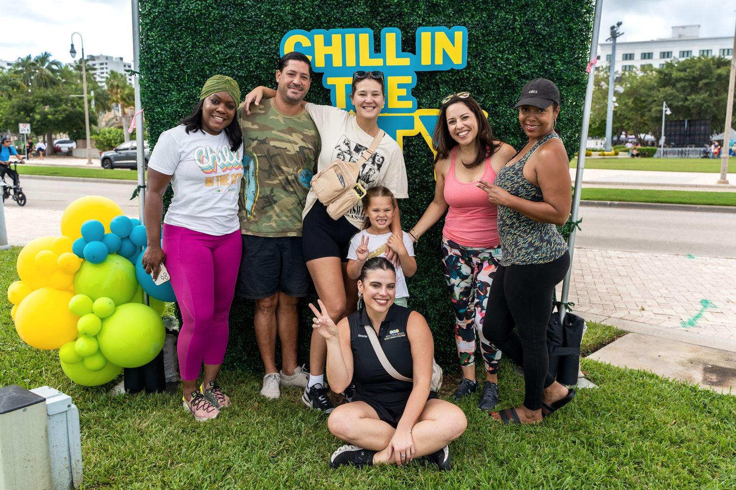 A group poses together outdoors in front of a yellow balloon arch with a 'Chill In' sign.