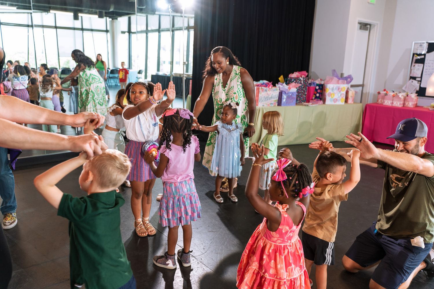 People dancing and having fun at an indoor celebration with colorful summer outfits.