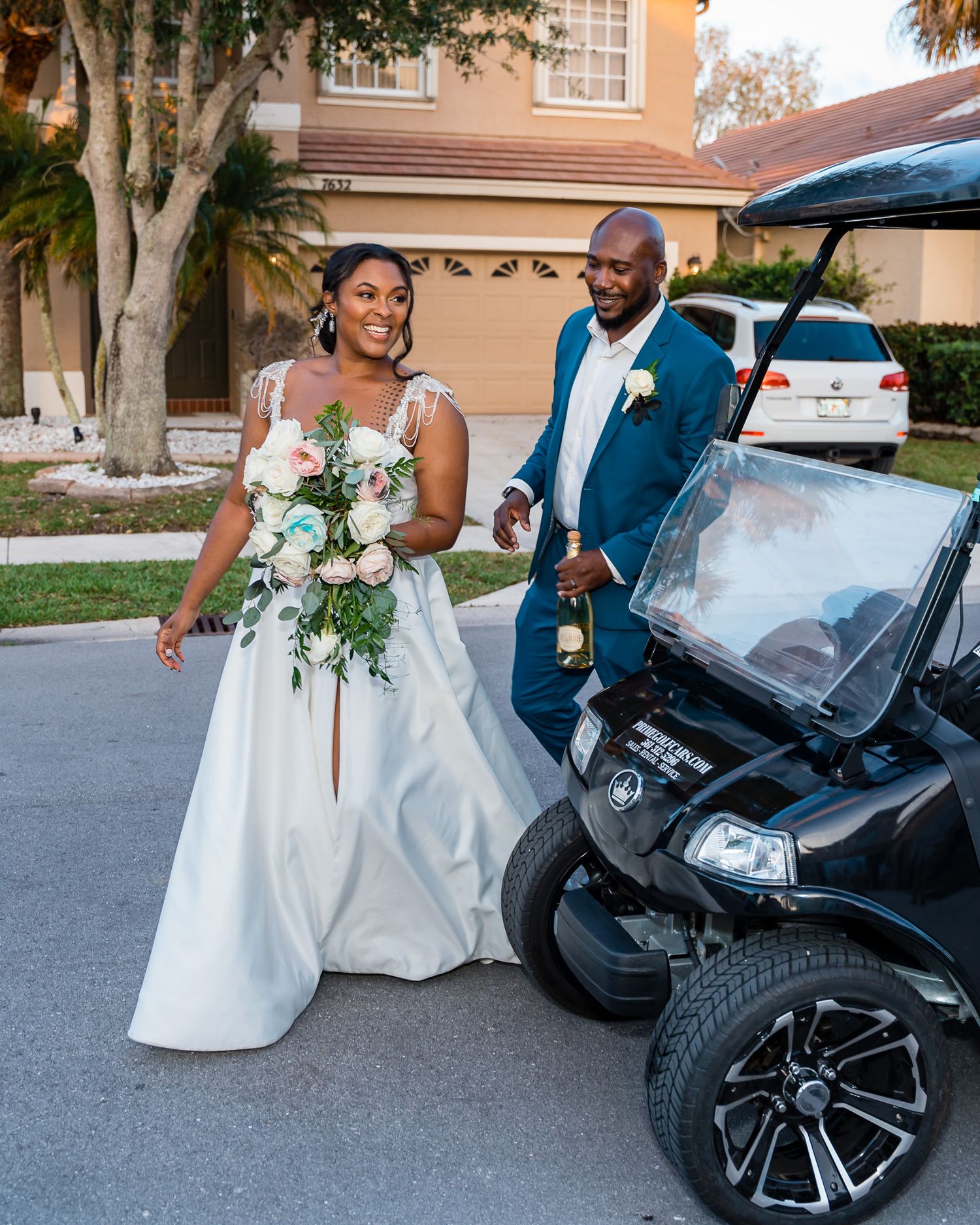 Wedding couple posing next to a black luxury golf cart.
