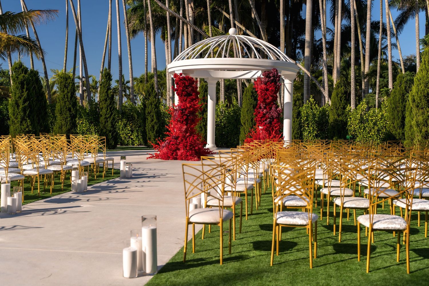 Outdoor wedding ceremony setup with white chairs and tropical palm trees lining a beachfront venue.
