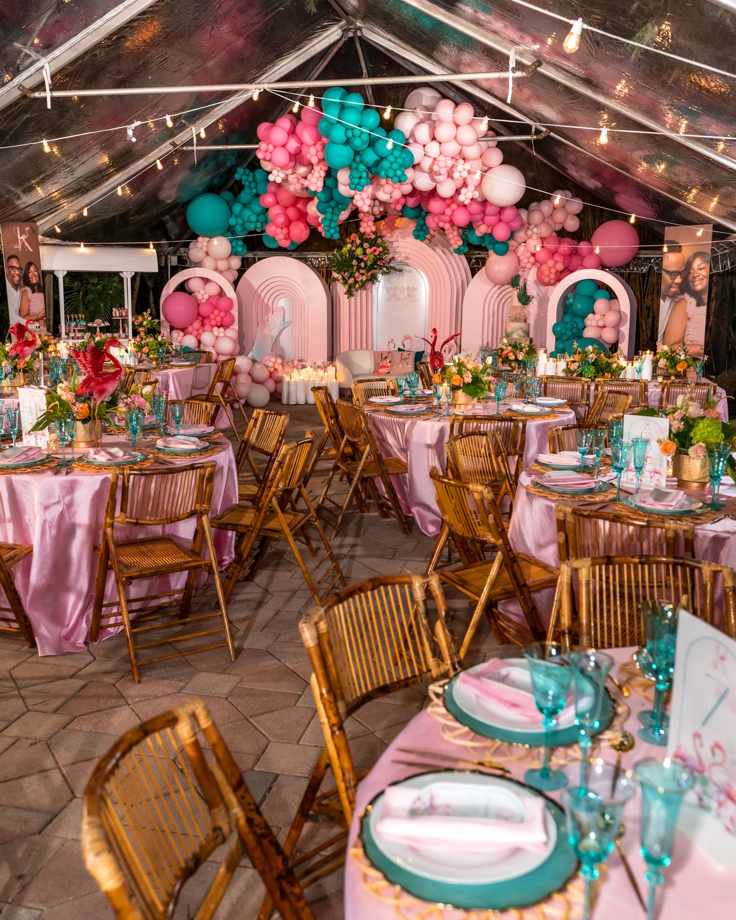 A wedding reception venue decorated with pink and teal balloon arches and wooden chairs.