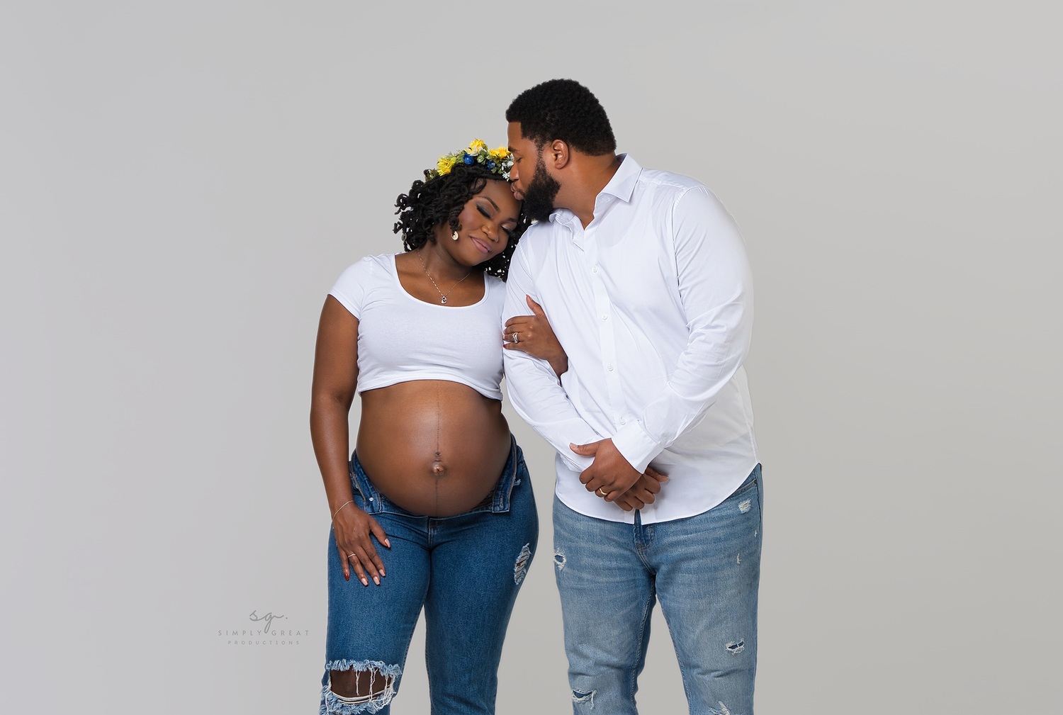 Sweet maternity moment with couple in coordinated white and denim outfits.