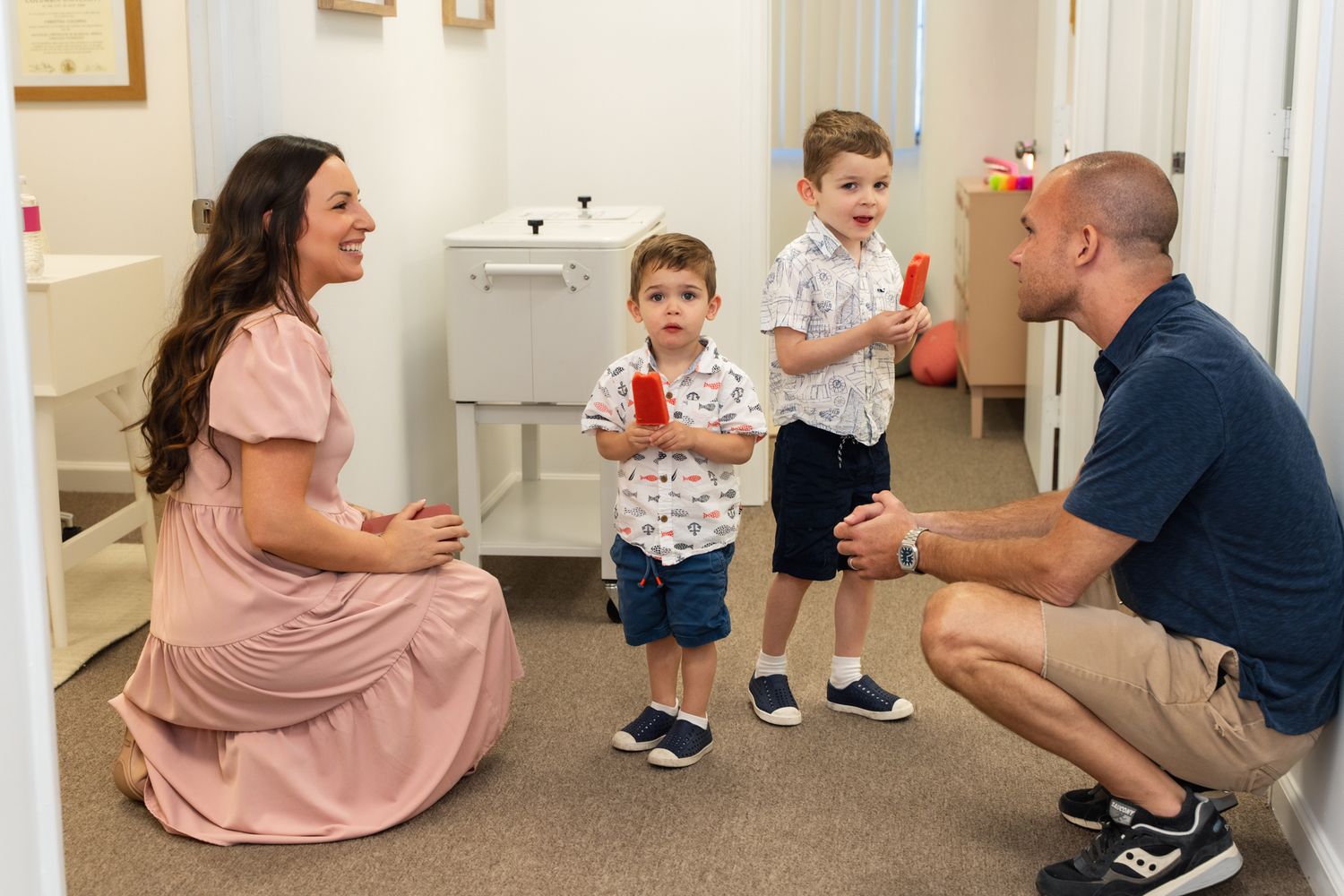 Family engaging in playful interaction in a well-lit indoor space.