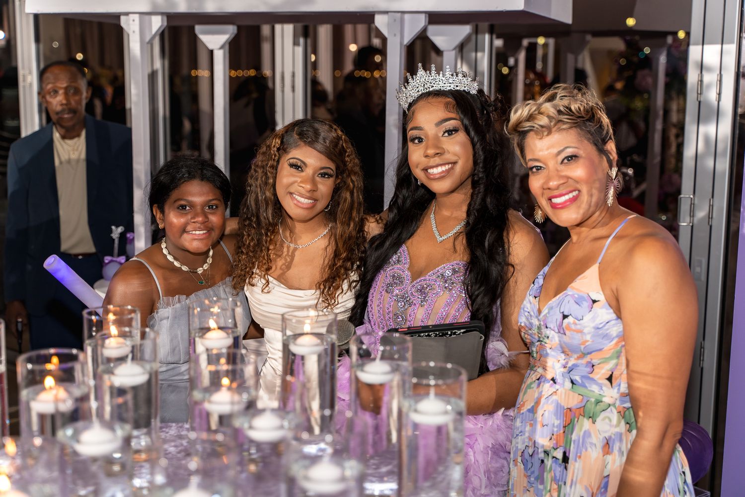Party guests enjoying celebration at elegant purple-themed event with glassware and decorations.