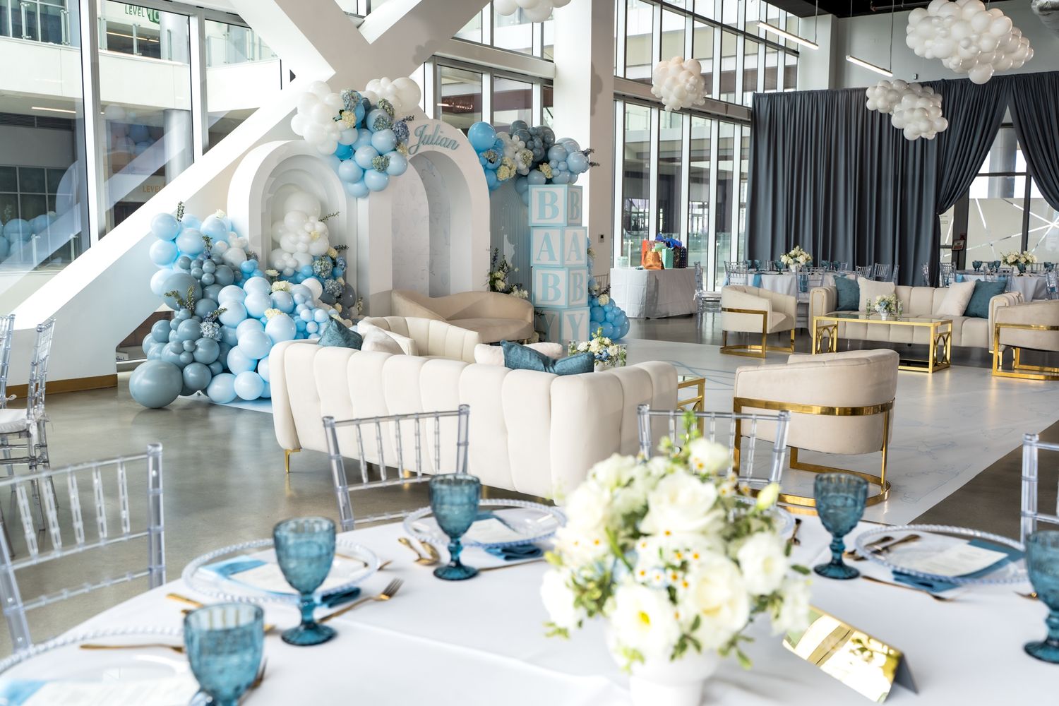 Modern event space decorated with blue and white balloon arrangements and floral centerpieces.