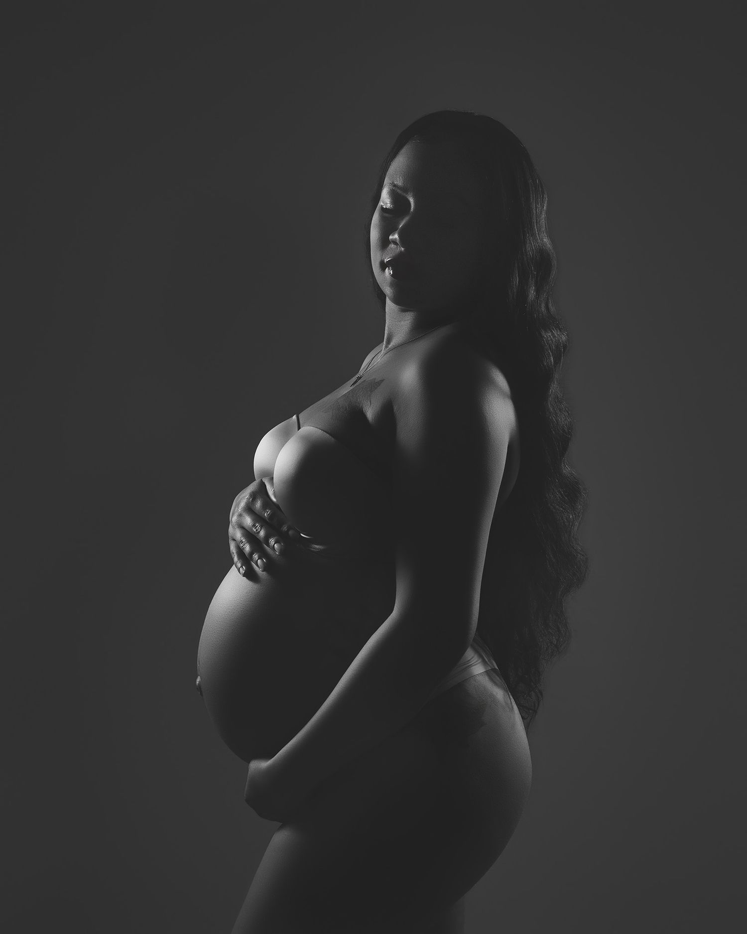 Artistic black and white maternity silhouette highlighting pregnant form.