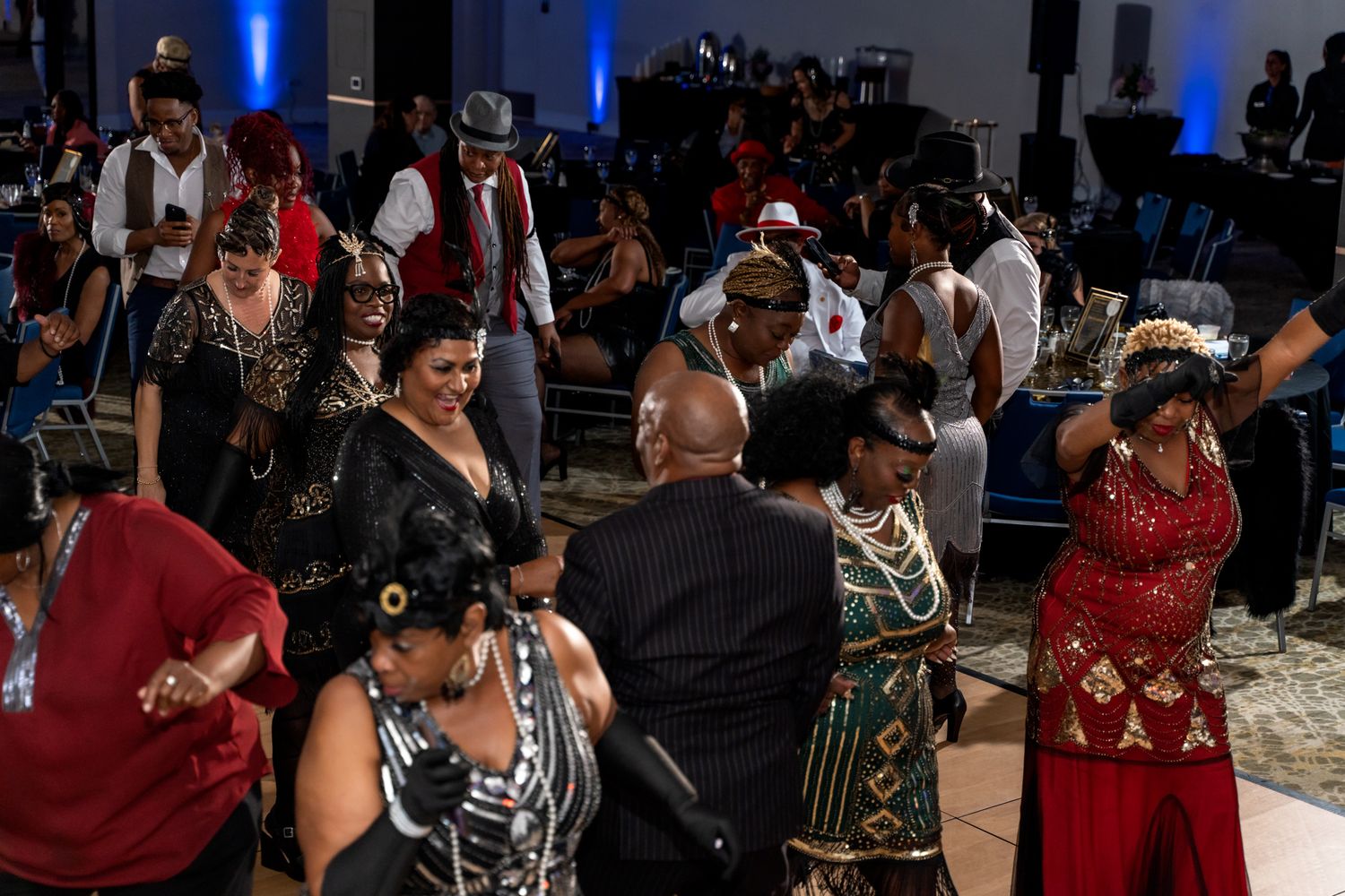 A lively crowd of party guests in formal attire dancing and socializing at an evening event.